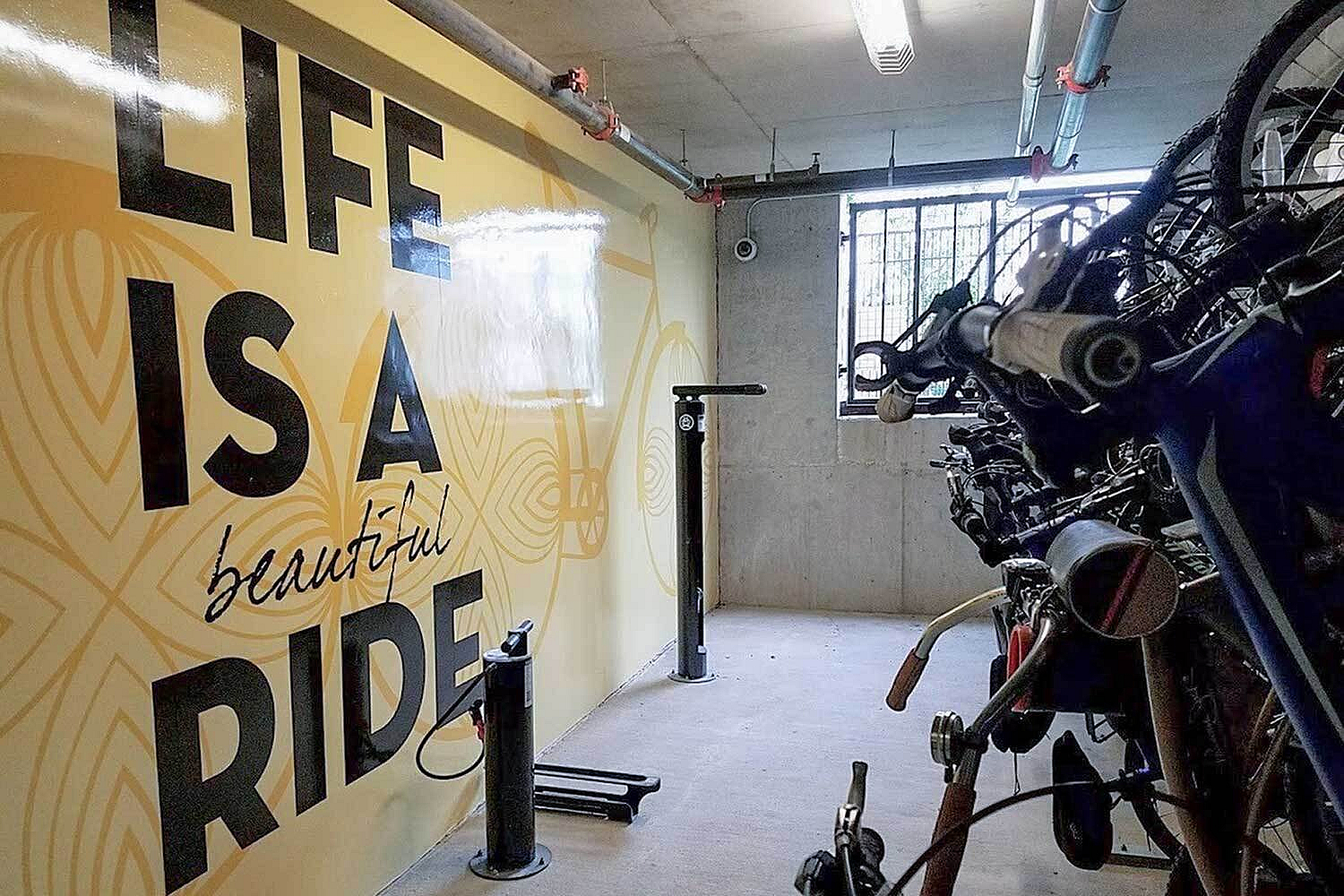 Vibrant bike storage room with bold motivational mural and ample bike racks, featuring bright lighting and a modern, industrial vibe.