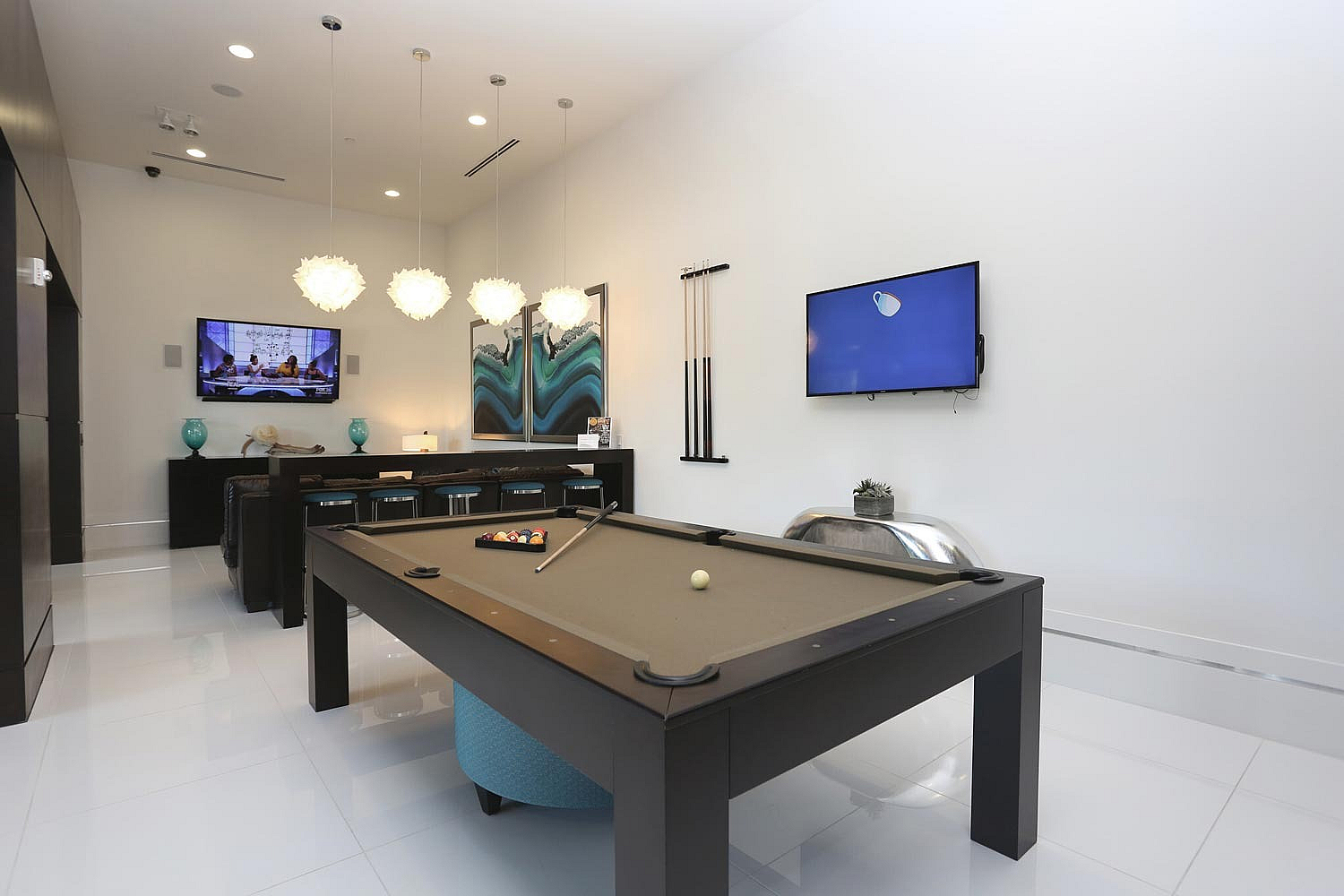 Elegant game room with a modern pool table, stylish pendant lighting, and sleek entertainment setup.