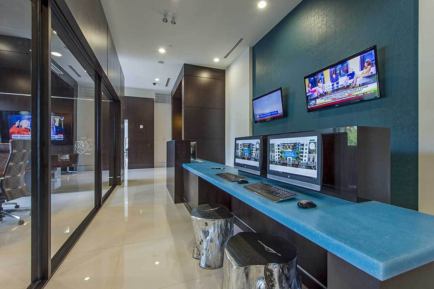 Modern office space with sleek glass partitions, dual computer workstations, and mounted televisions for a dynamic work environment.