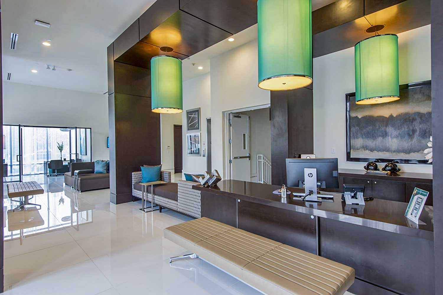 Elegant apartment lobby with modern decor, featuring bright pendant lighting, sleek reception desk, and cozy seating area.