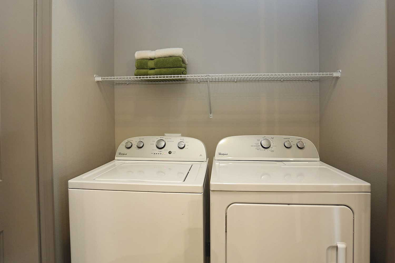 Modern laundry area with a sleek washer and dryer set, complemented by a minimalist shelf for storage.