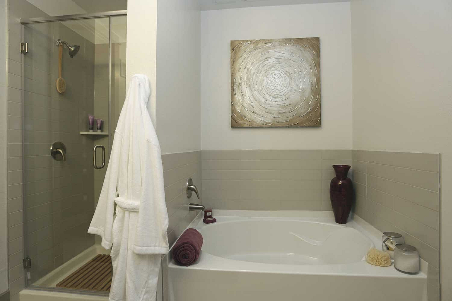 Elegant bathroom with a modern bathtub, glass-enclosed shower, and artistic wall decor, offering a spa-like retreat.