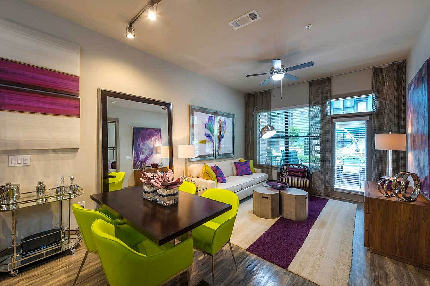 Contemporary living room with vibrant decor featuring lime green chairs, chic furniture, and floor-to-ceiling windows.