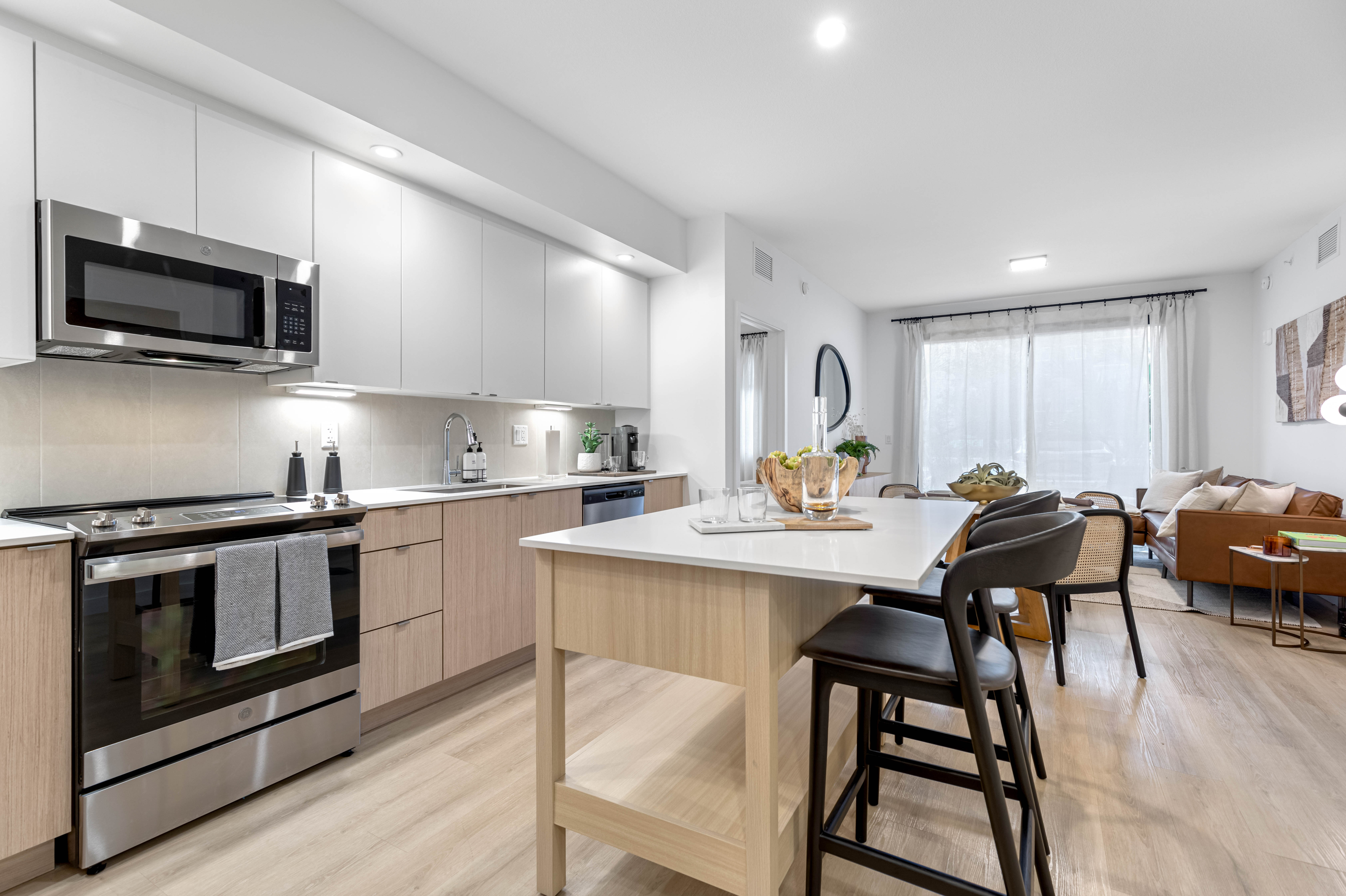 Modern open-concept kitchen and living area featuring sleek cabinetry, stainless steel appliances, and a welcoming dining space, perfect for vibrant urban living.