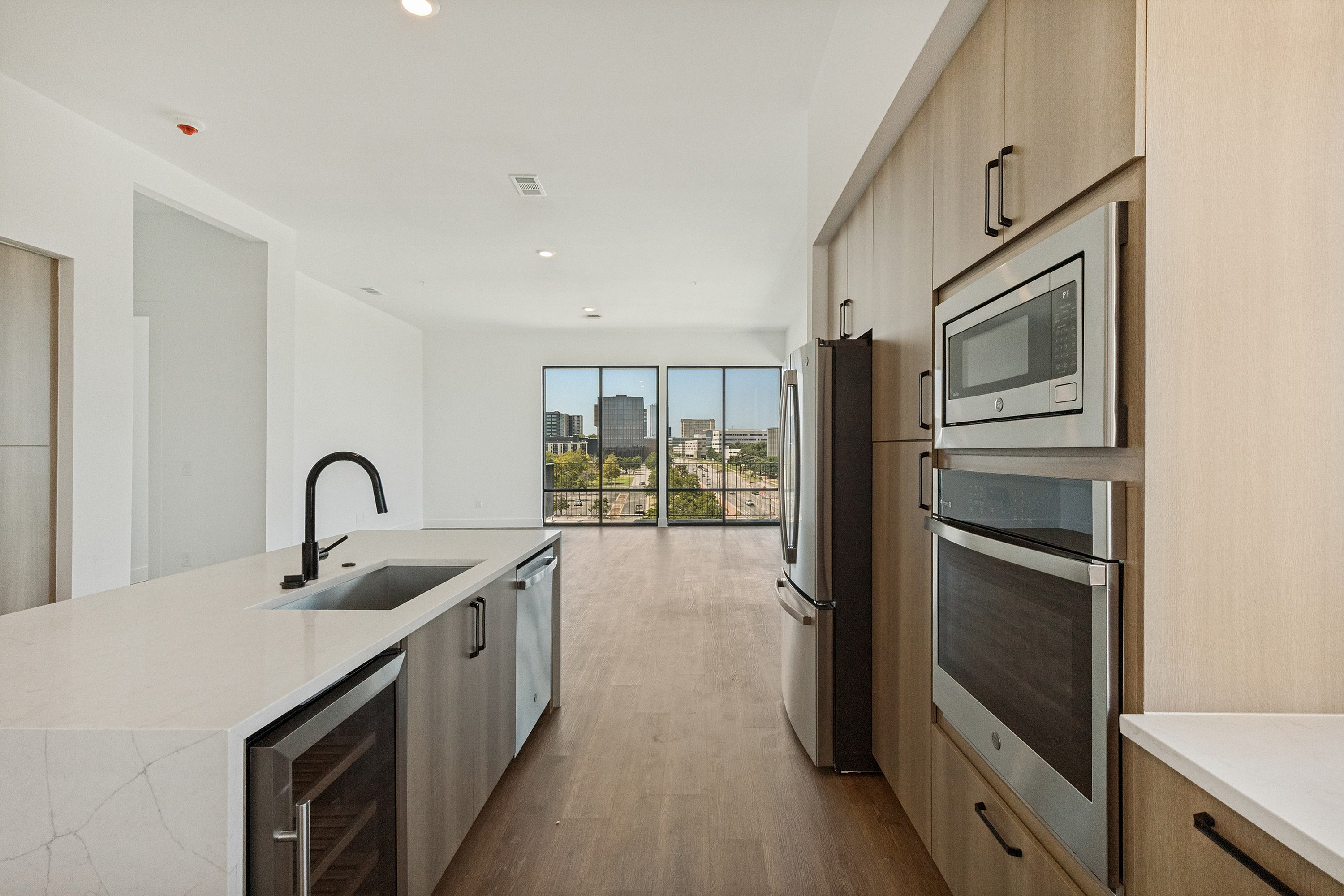 Modern open-concept kitchen with sleek appliances and stunning city view through floor-to-ceiling windows.