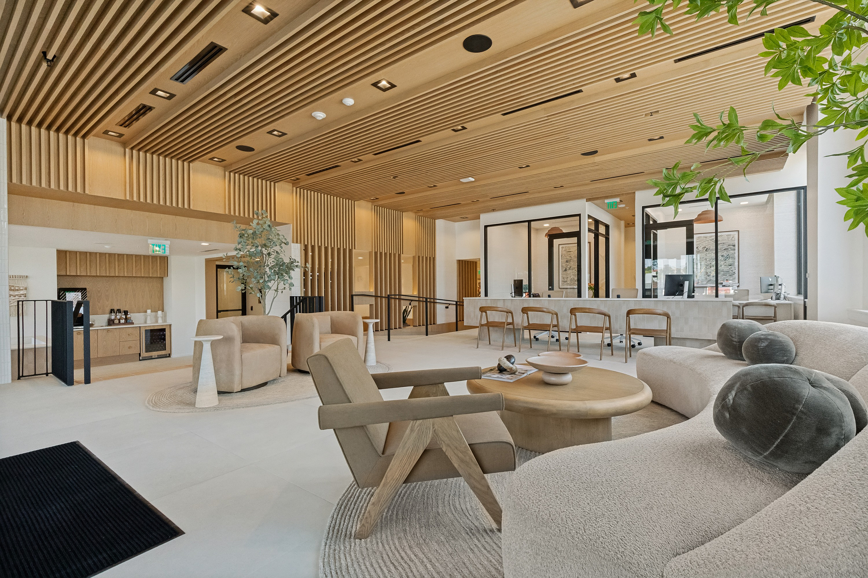 Luxurious modern lobby with sleek wooden accents, elegant neutral furniture, and abundant natural light creating a welcoming atmosphere.