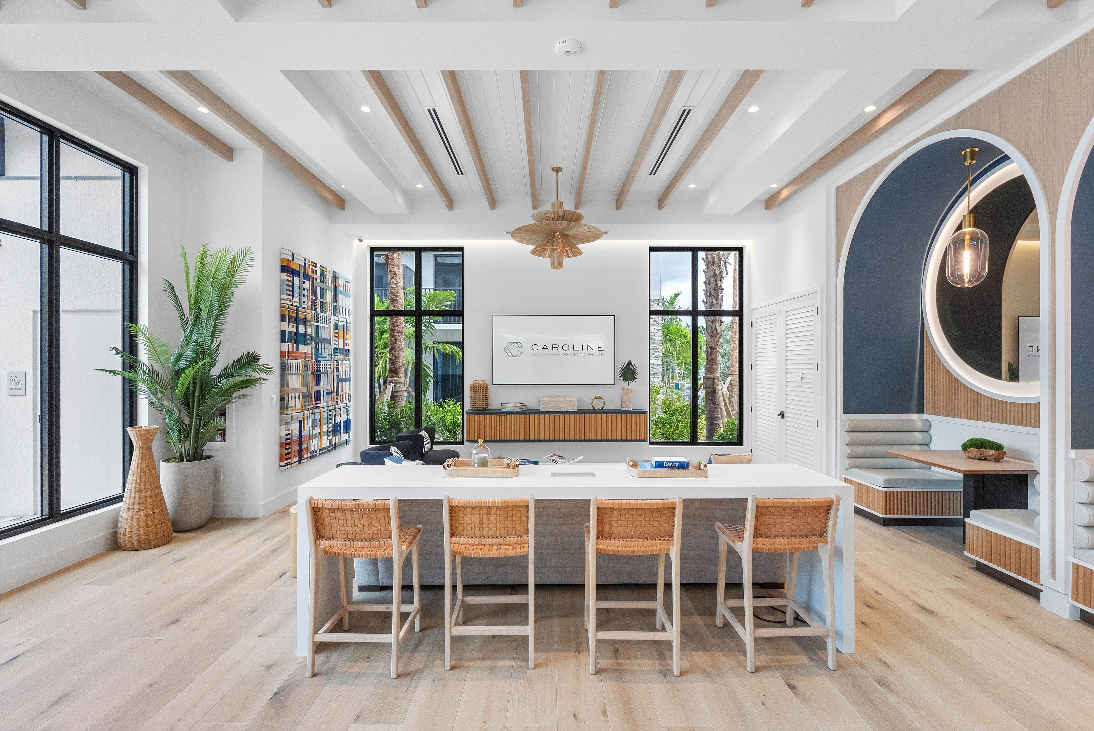 Modern communal lounge with elegant decor, featuring sleek ceiling beams, stylish wall art, and abundant natural light from large windows.