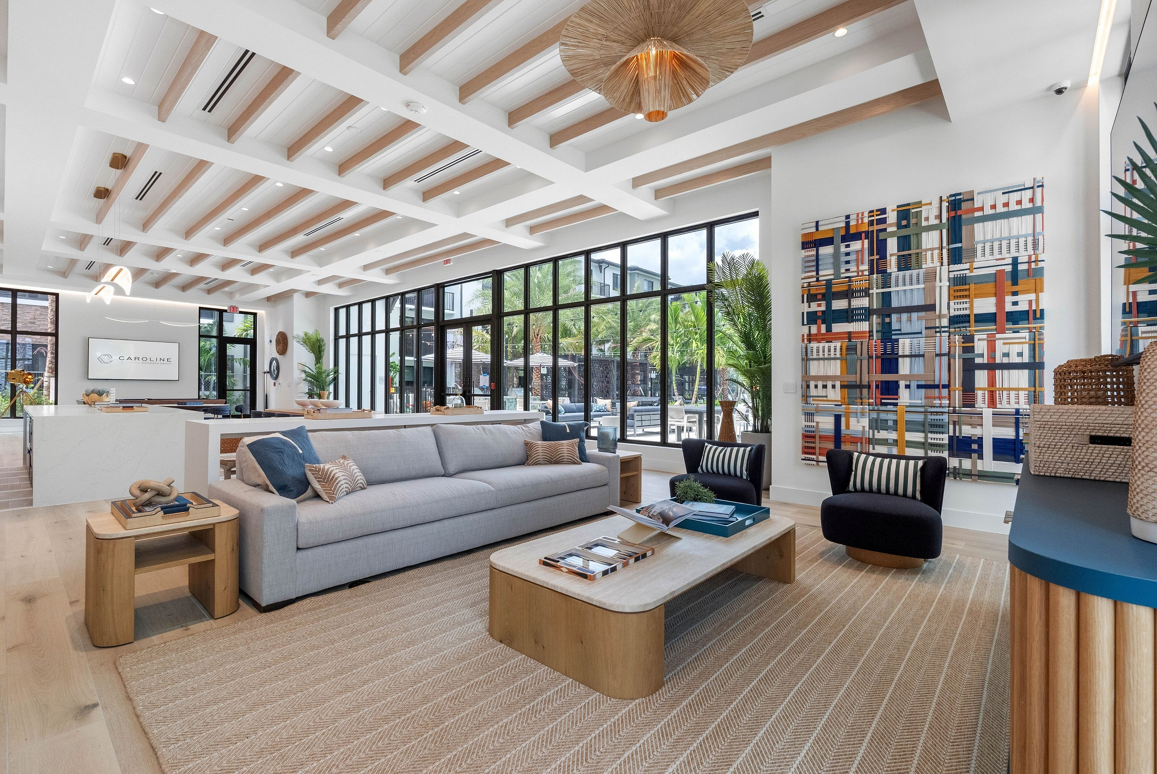 Luxurious and modern living room with floor-to-ceiling windows, elegant decor, and vibrant artwork, offering a bright and inviting atmosphere.