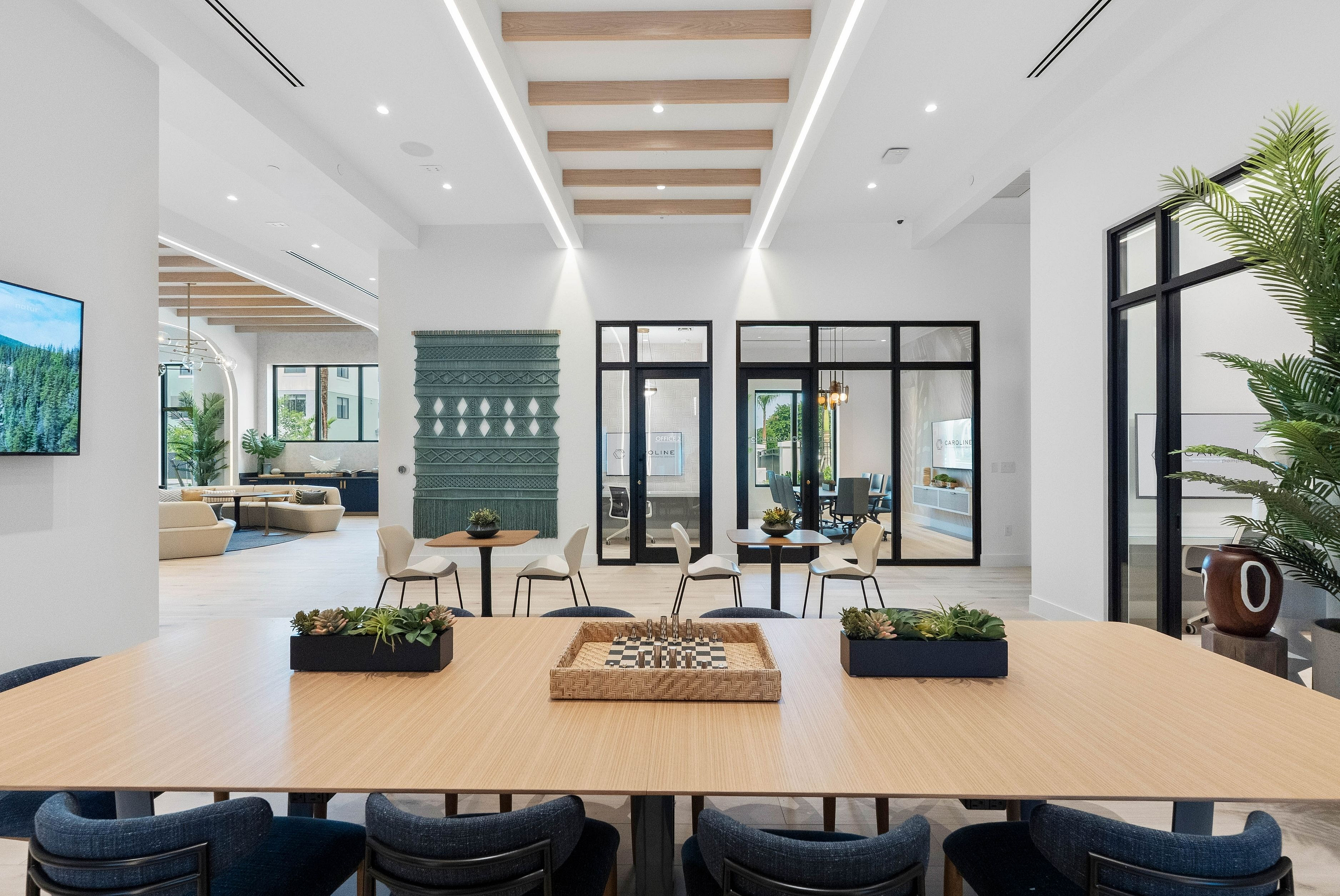 Elegant modern interior with chic wooden ceiling beams, abundant natural light, and stylish seating areas, perfect for gatherings and relaxation.