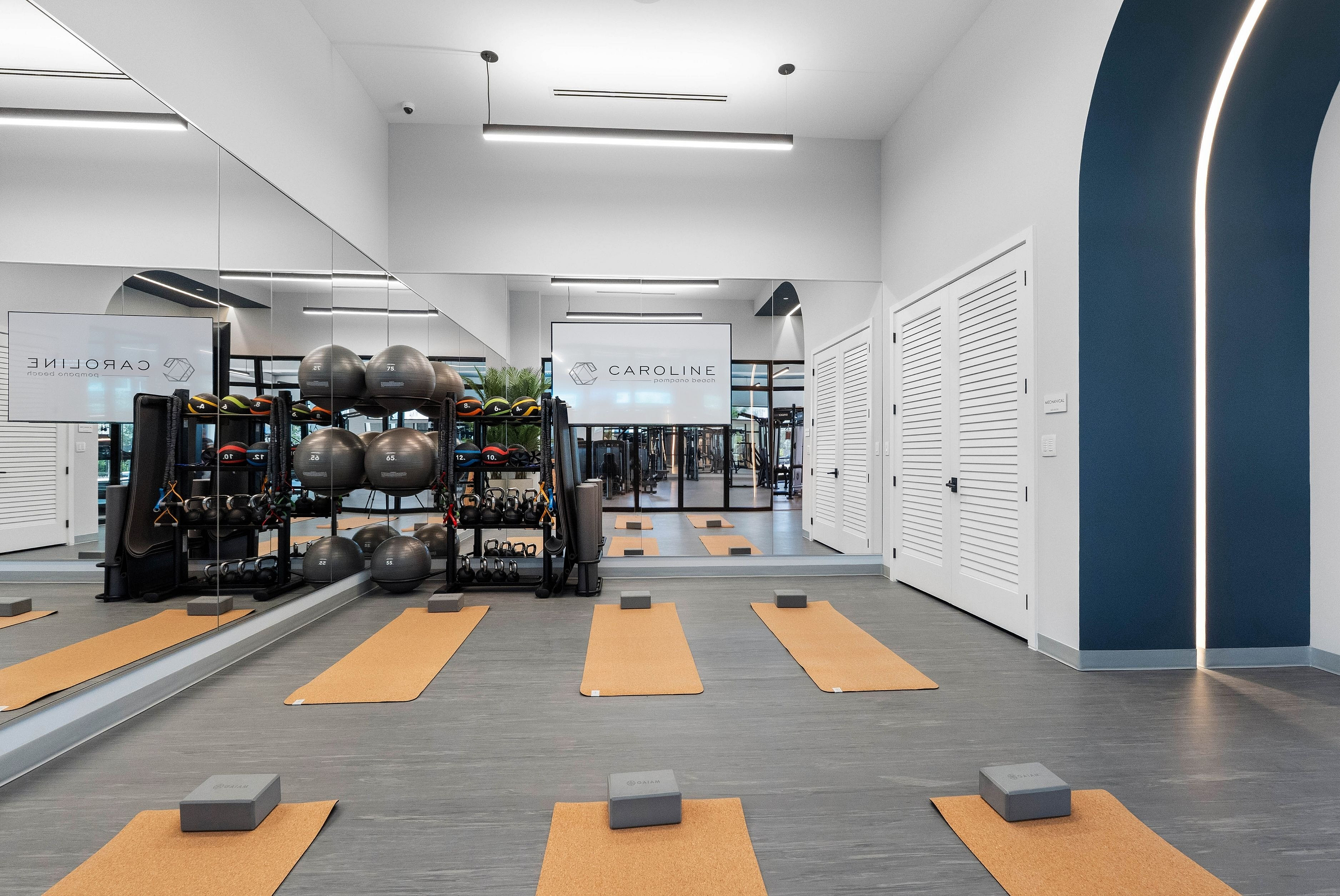 Luxurious fitness studio featuring sleek yoga mats, mirrored walls, and a complete range of workout equipment at Caroline Pompano Beach.