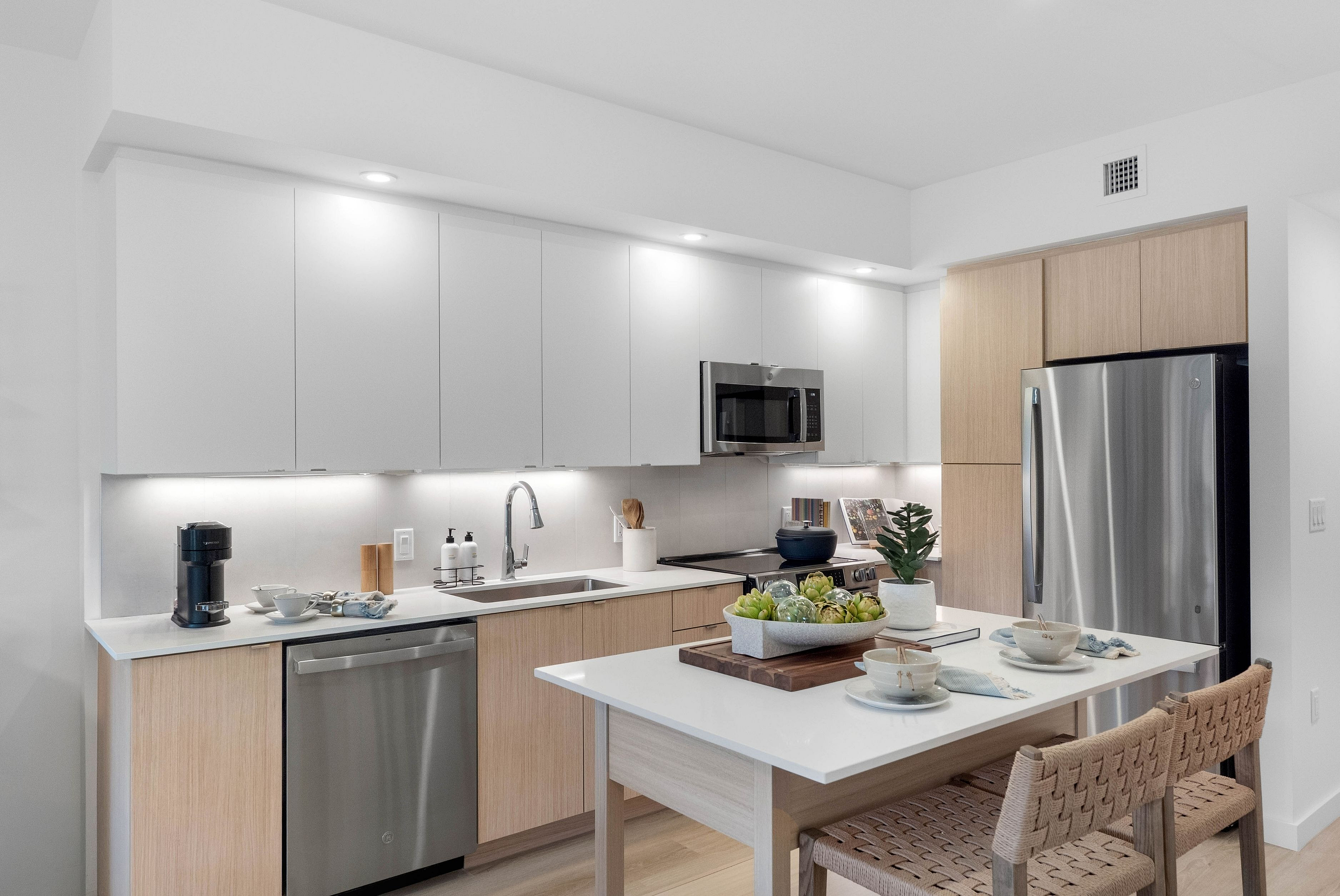 Modern kitchen with sleek white cabinetry, stainless steel appliances, and a chic breakfast bar, perfect for contemporary living.