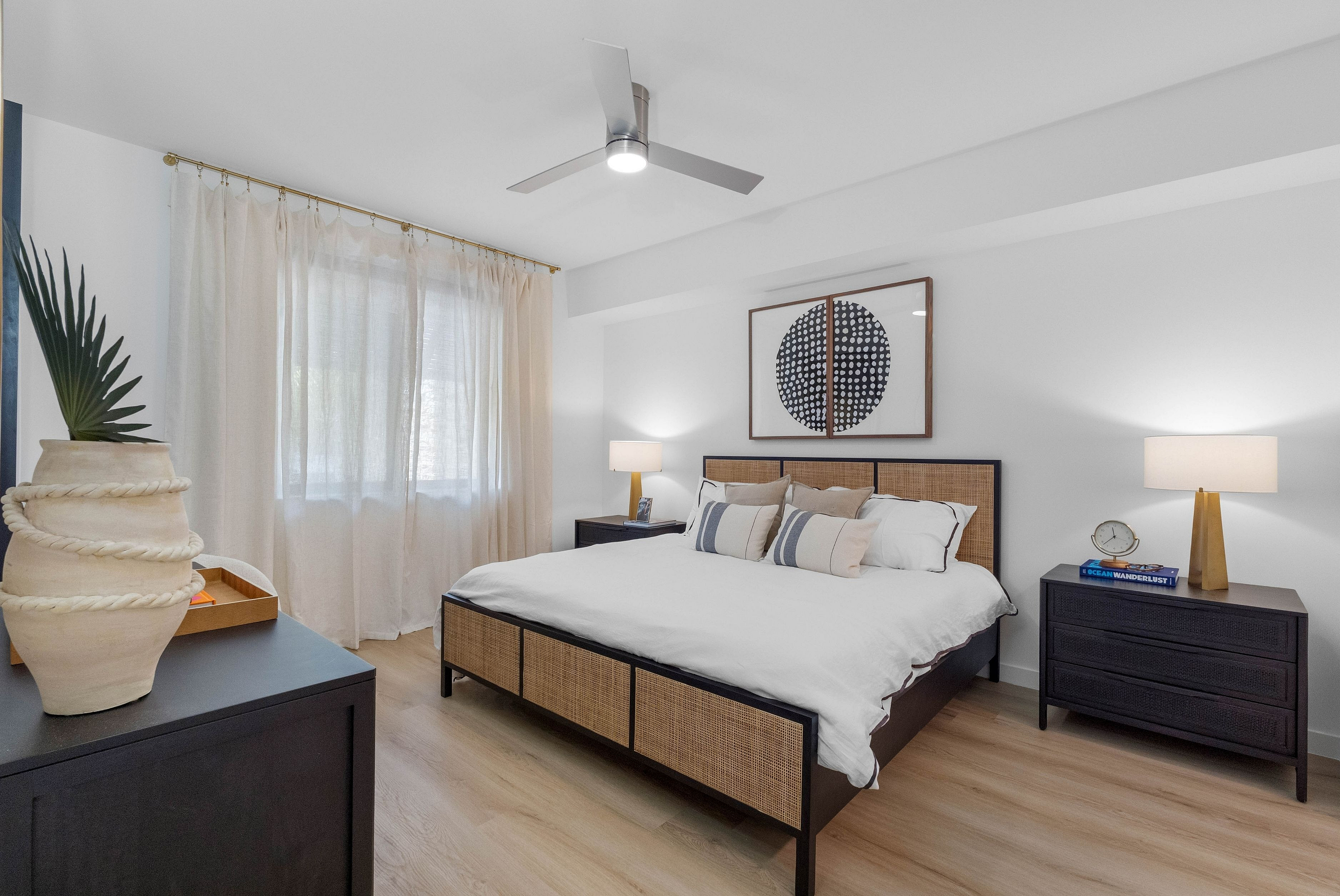 Inviting bedroom with elegant decor, natural light, and modern ceiling fan, offering a tranquil retreat.