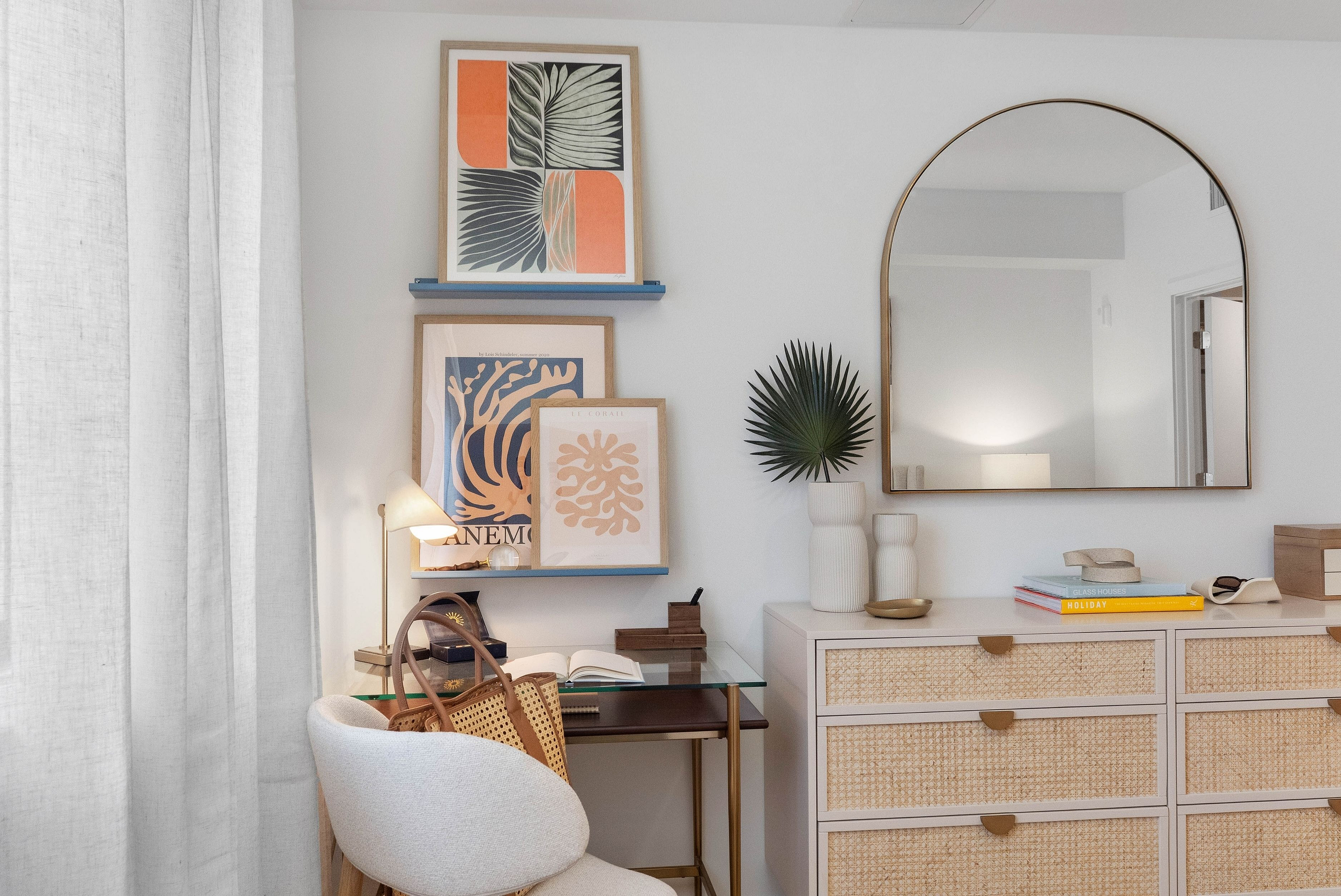 Chic and cozy home office featuring modern decor, vibrant artwork, elegant mirror, and stylish woven furniture.