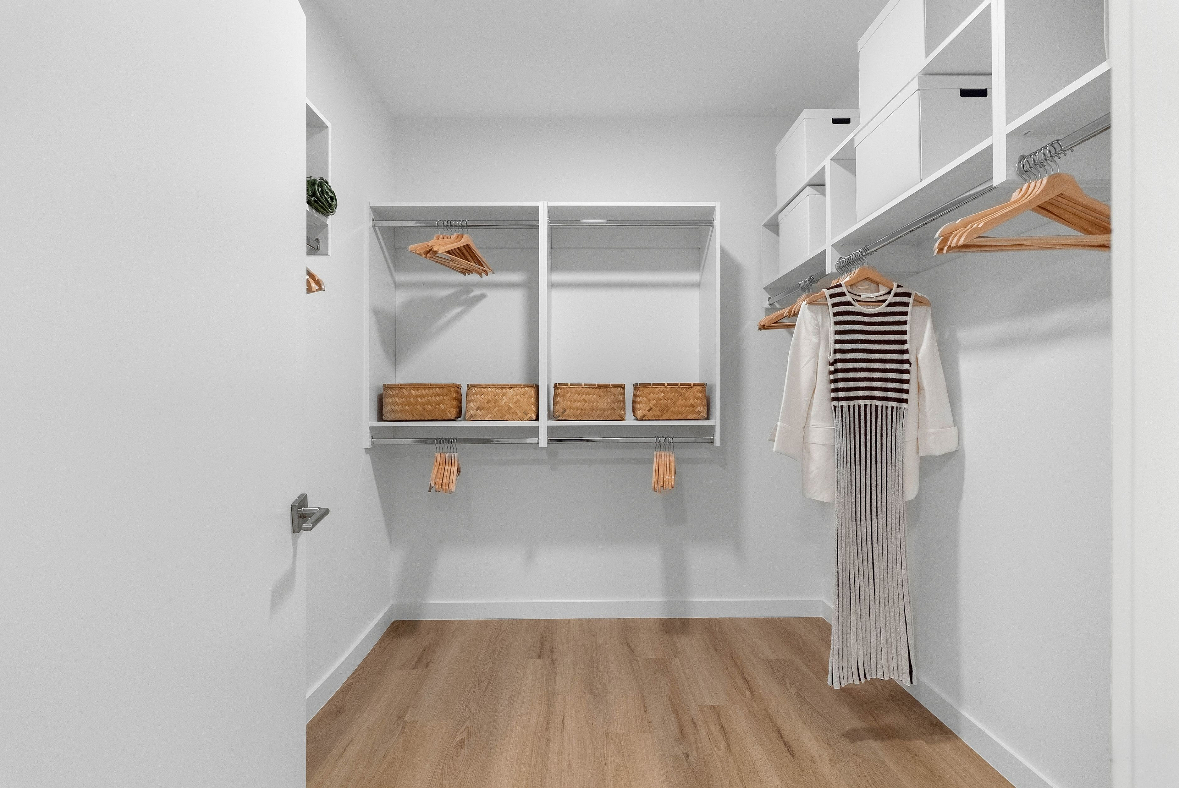 Elegantly designed walk-in closet featuring ample shelving, wooden hangers, and stylish storage baskets.