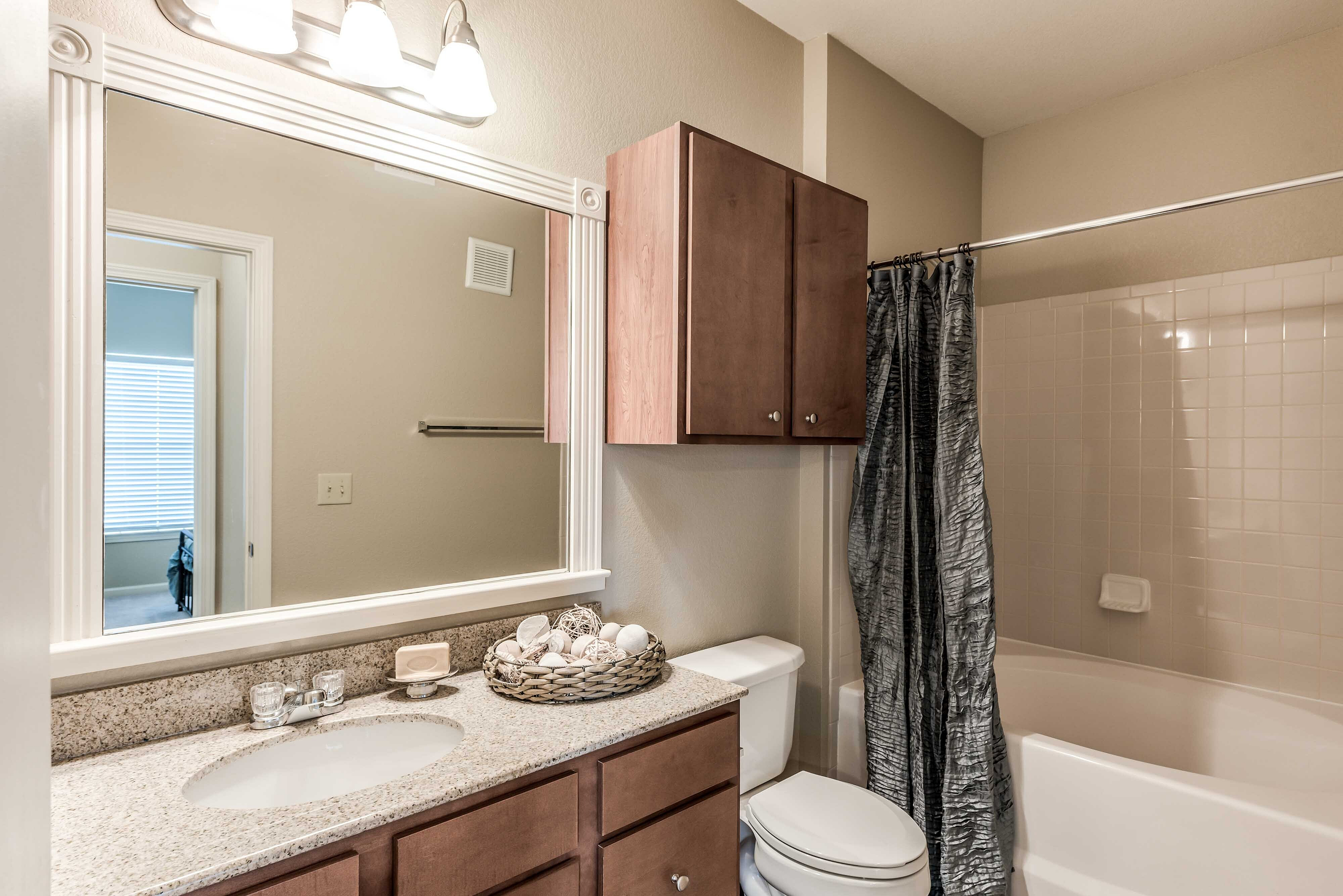 Apartment bathroom with vanity and wood-tone cabinetry at Bennett Baytown