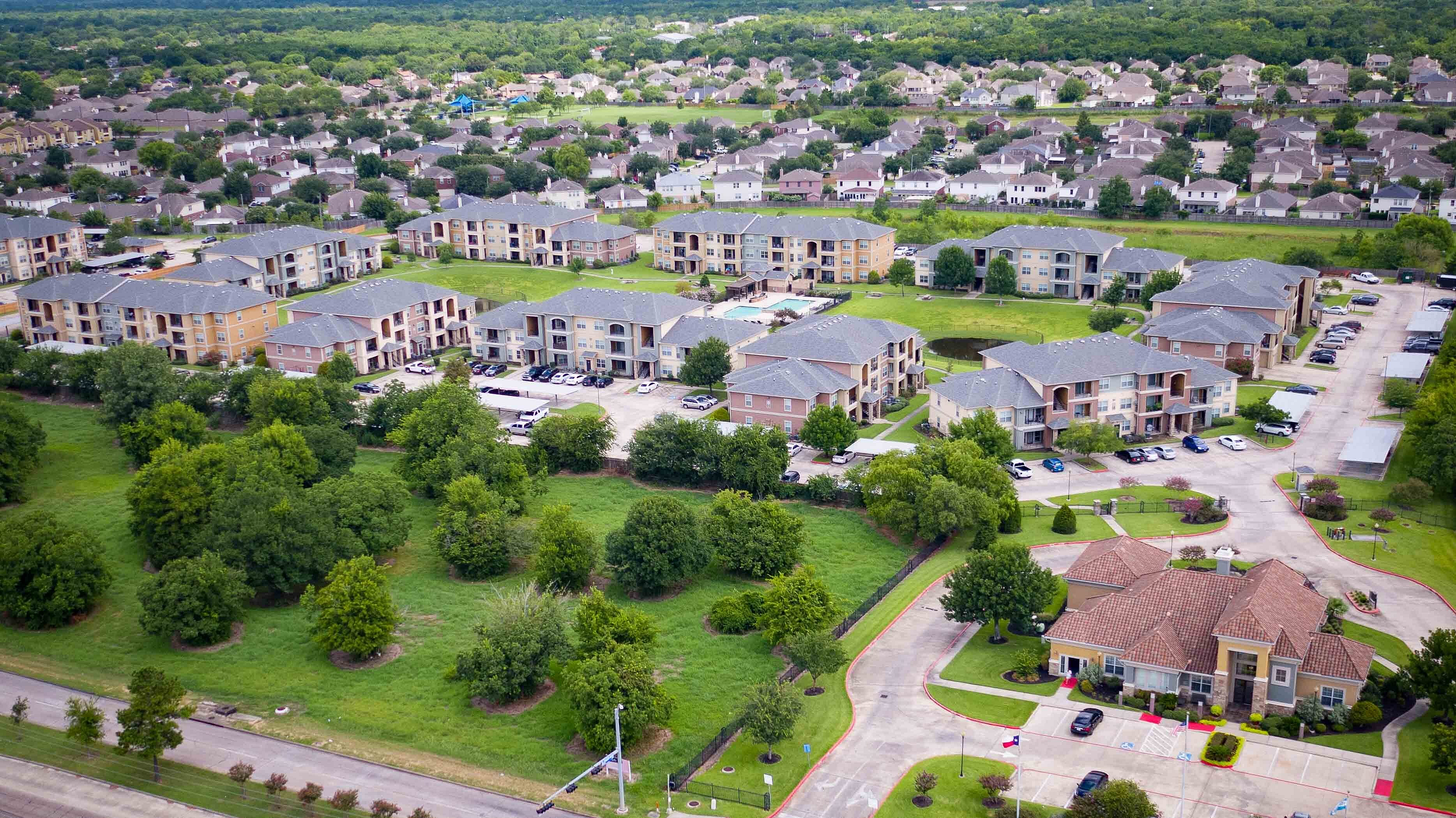 Aerial view of apartment community buildings, green space, and parking