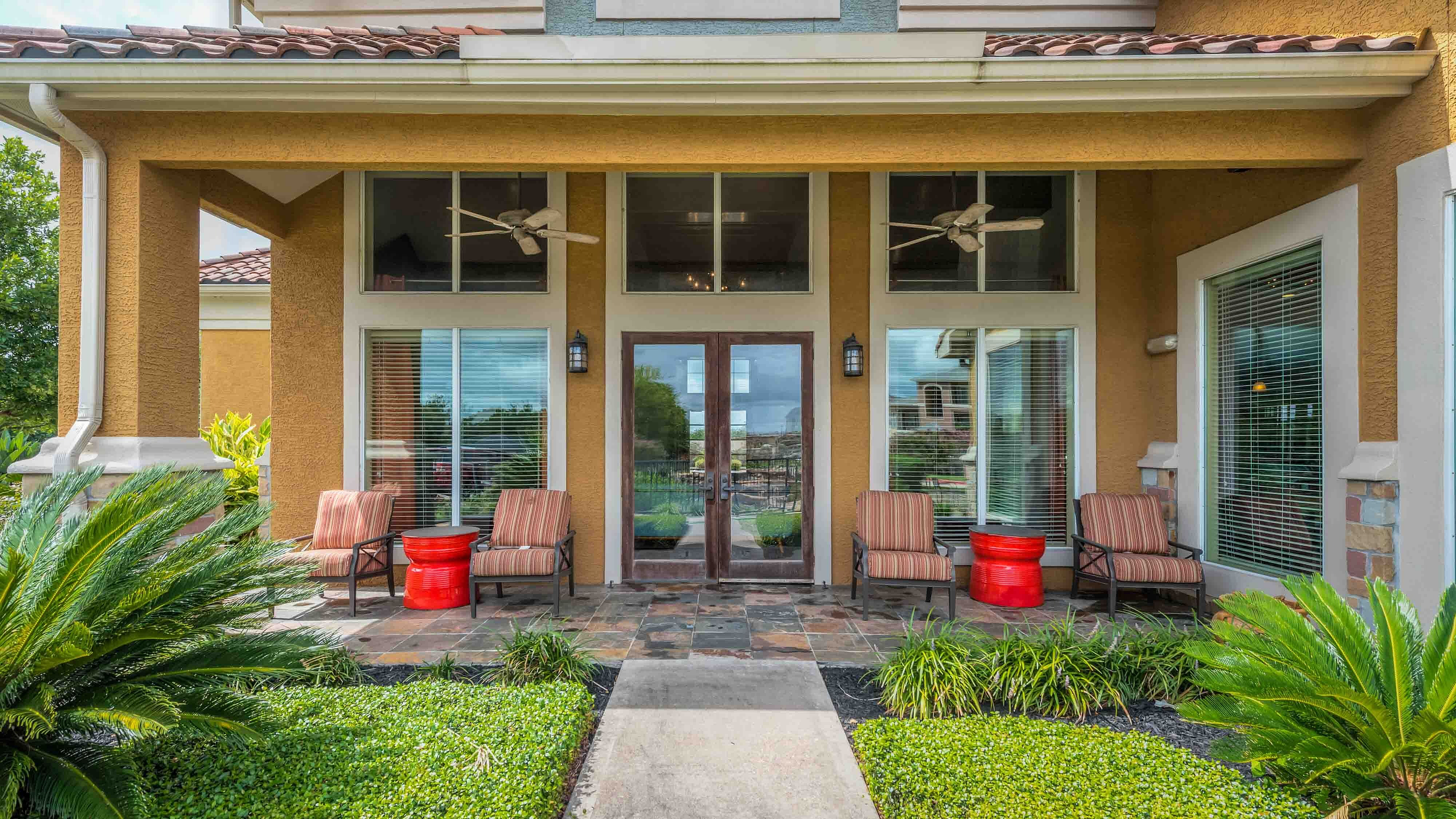 Apartment clubhouse entrance with covered patio and landscaping