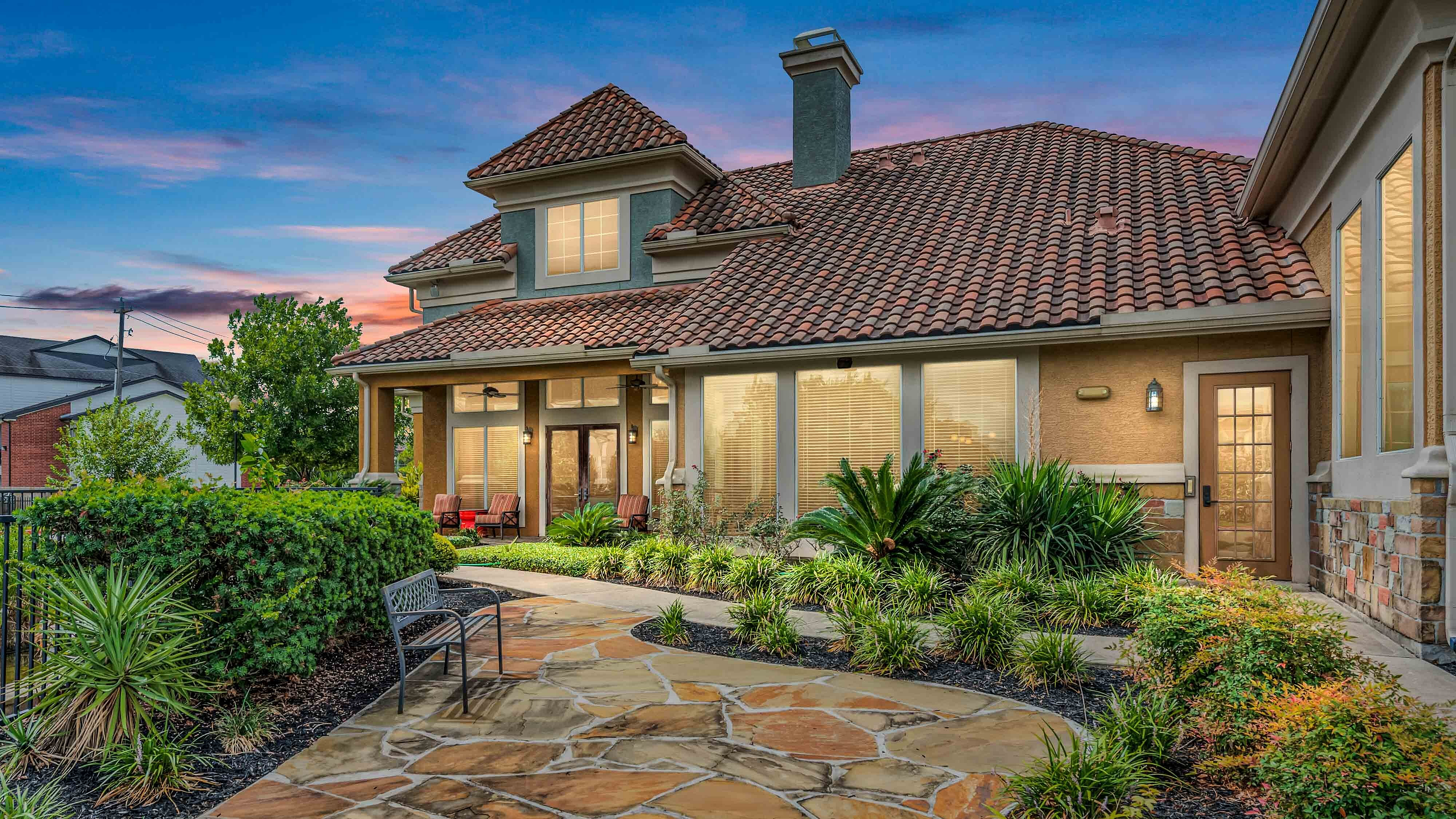 Apartment clubhouse exterior with terracotta roof and landscaped grounds