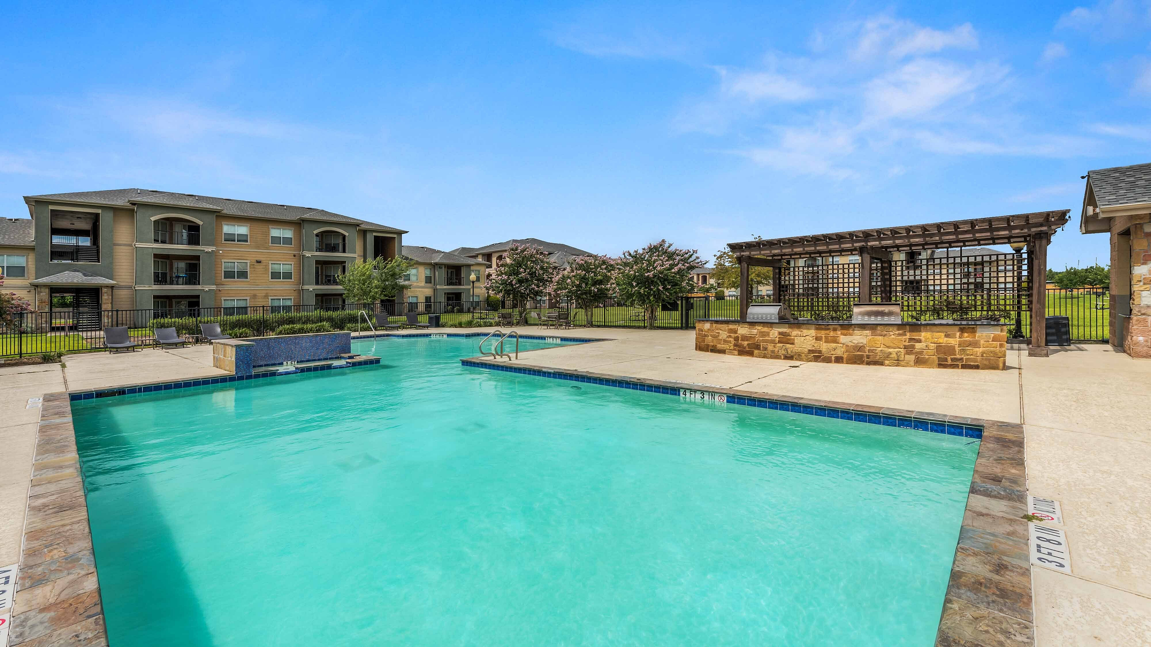 Community swimming pool with lounge chairs and apartment buildings