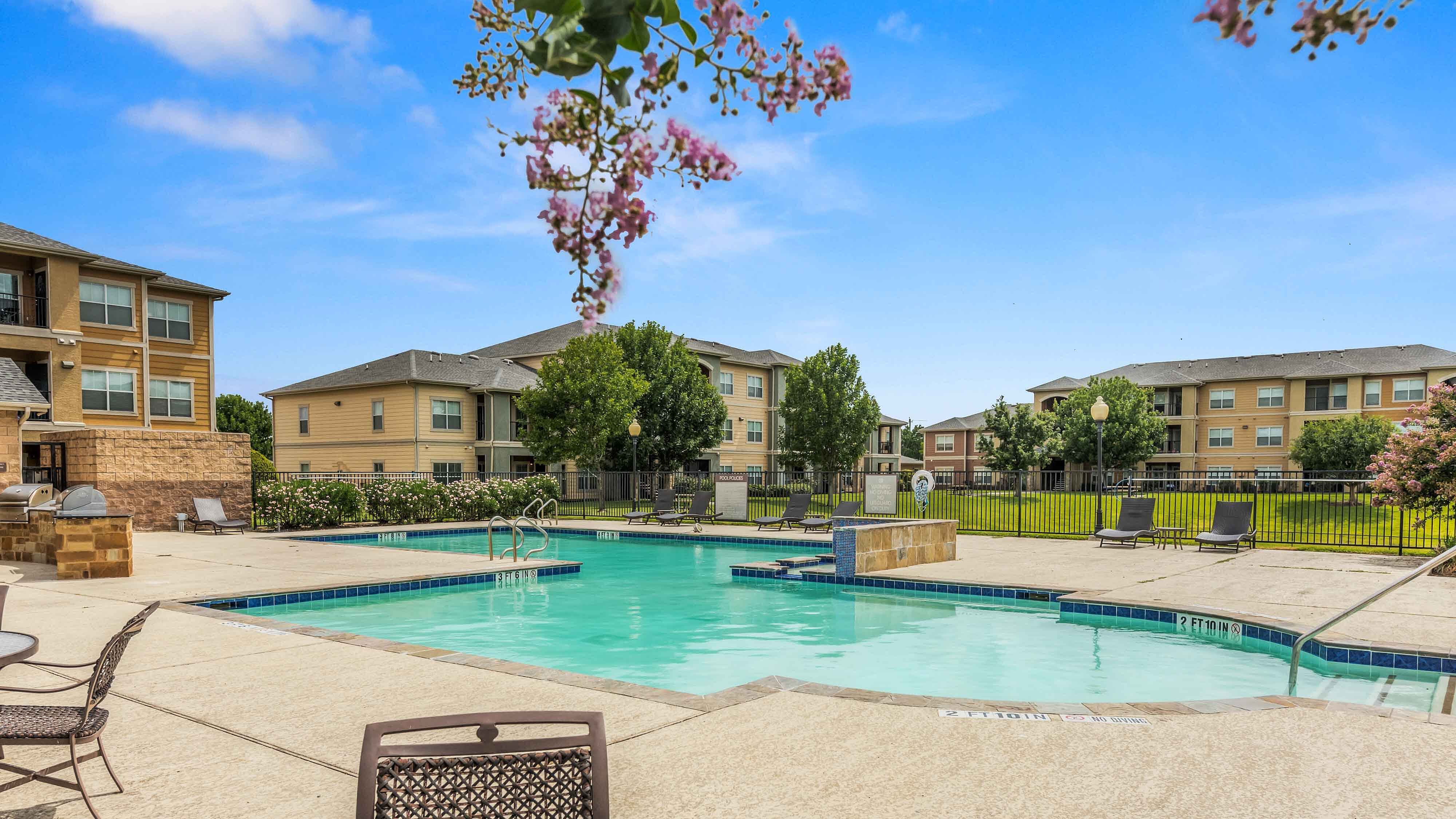Community swimming pool with lounge chairs and landscaped surroundings
