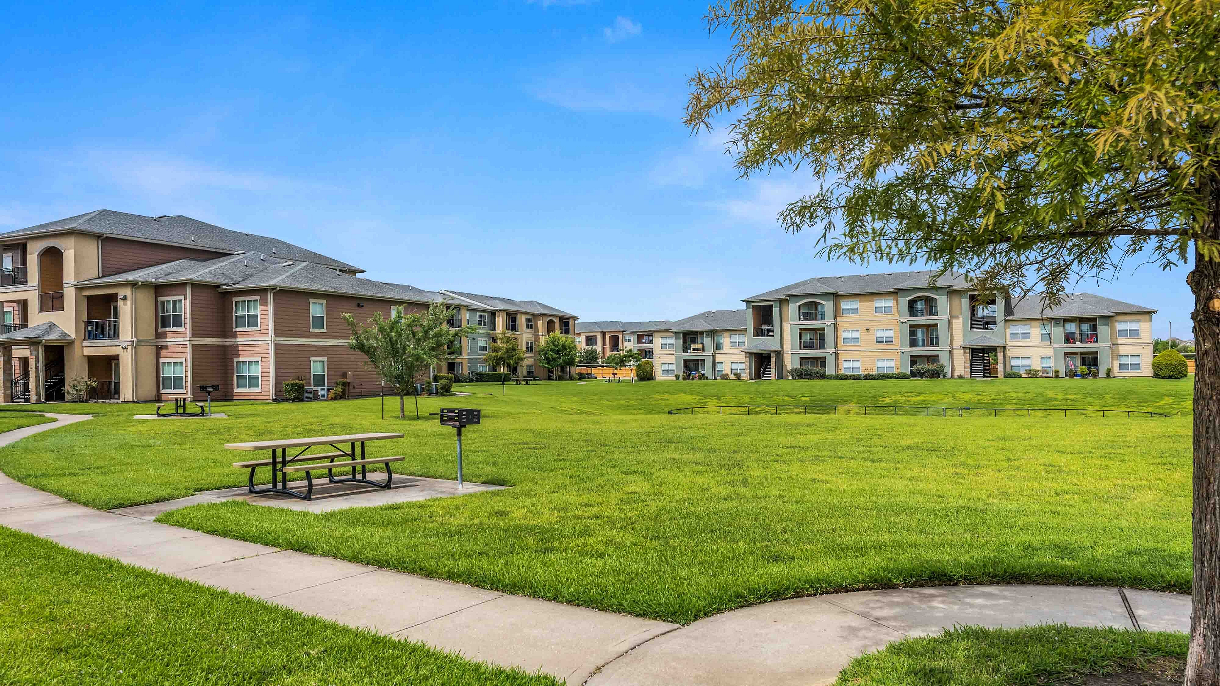 Landscaped community green space with walking paths, picnic tables, and barbecue areas