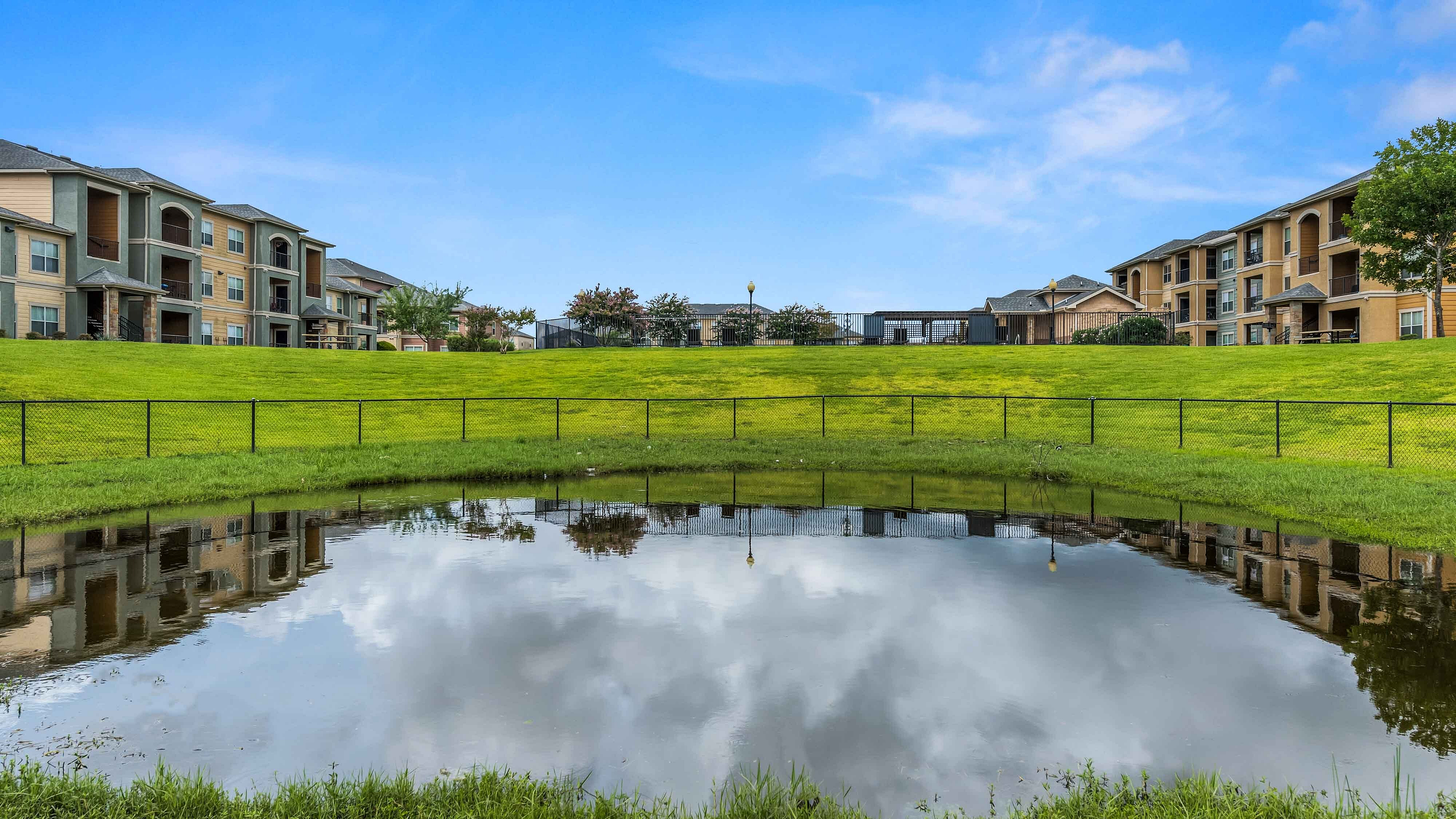 Community pond surrounded by lush landscape and greenbelt