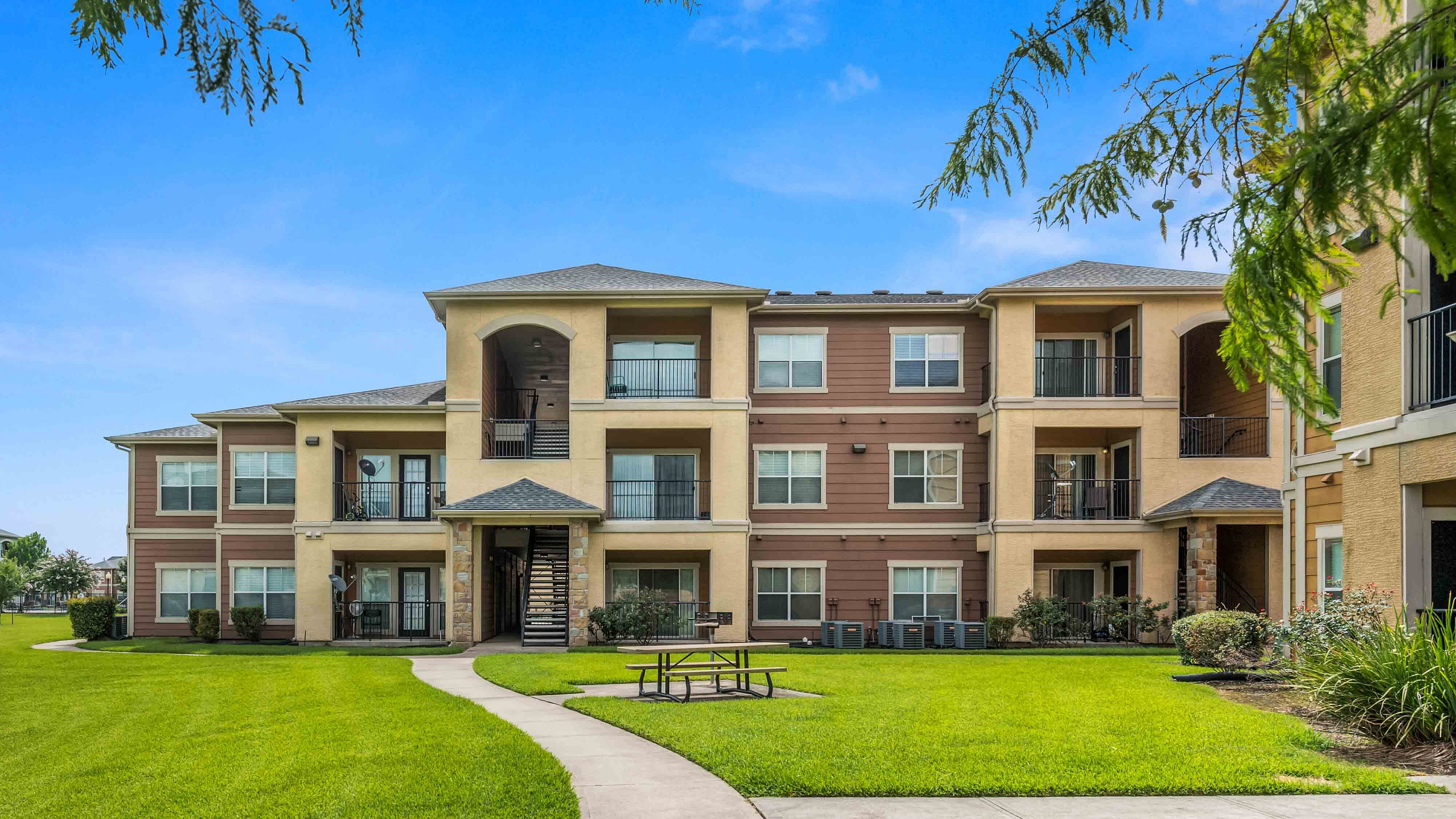 Exterior view of apartment building with balconies and landscaped lawn