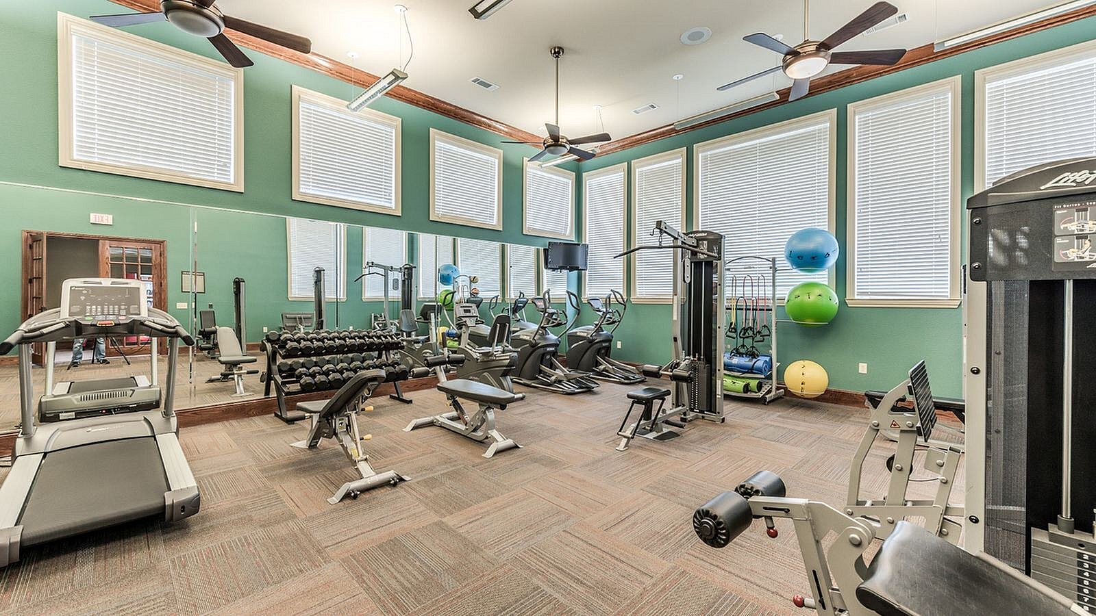 Apartment fitness center with treadmills, ellipticals, free weights, and strength equipment