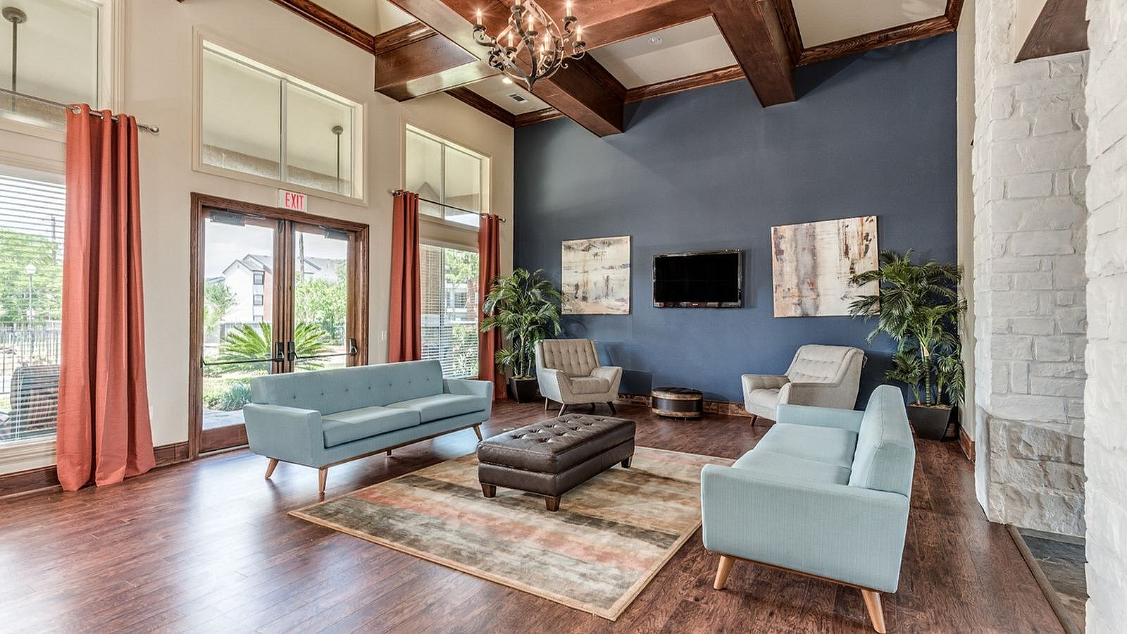 Resident clubhouse lounge with comfortable seating, fireplace, high ceilings, and large windows