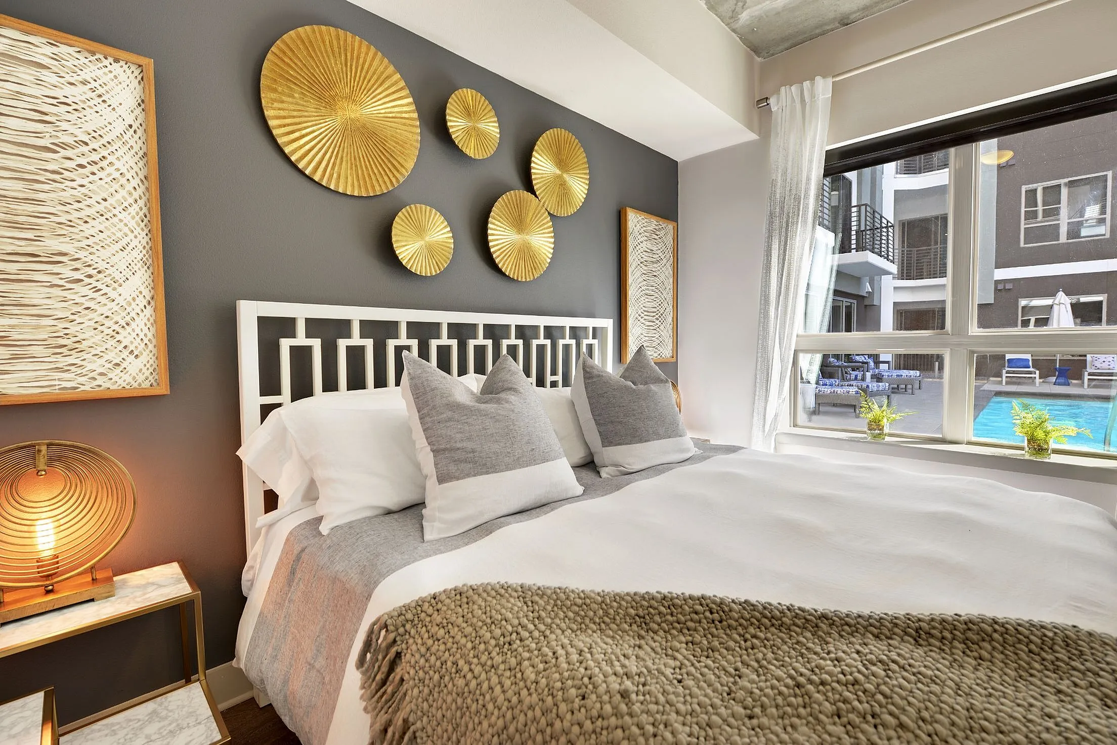 Bedroom with bed, gold wall art and window with pool view