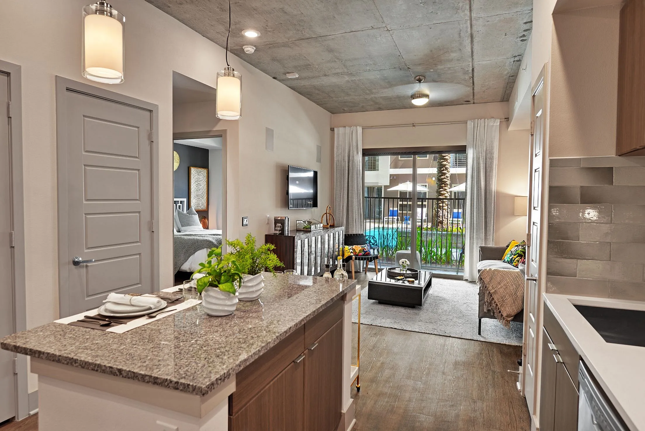 Kitchen island with granite counter, pendant lights and living room with balcony door
