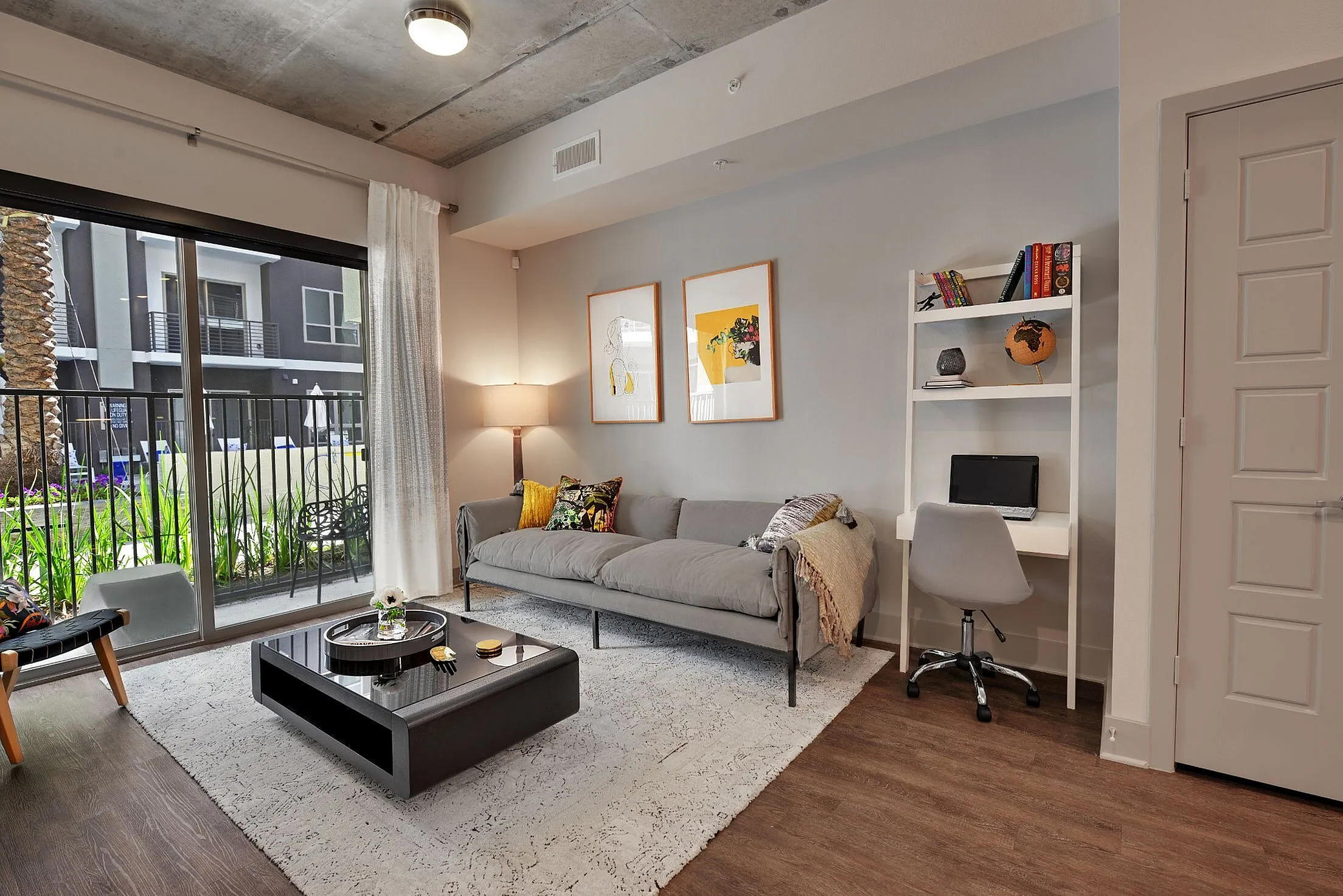 Living room with sofa, coffee table, desk nook and sliding glass door