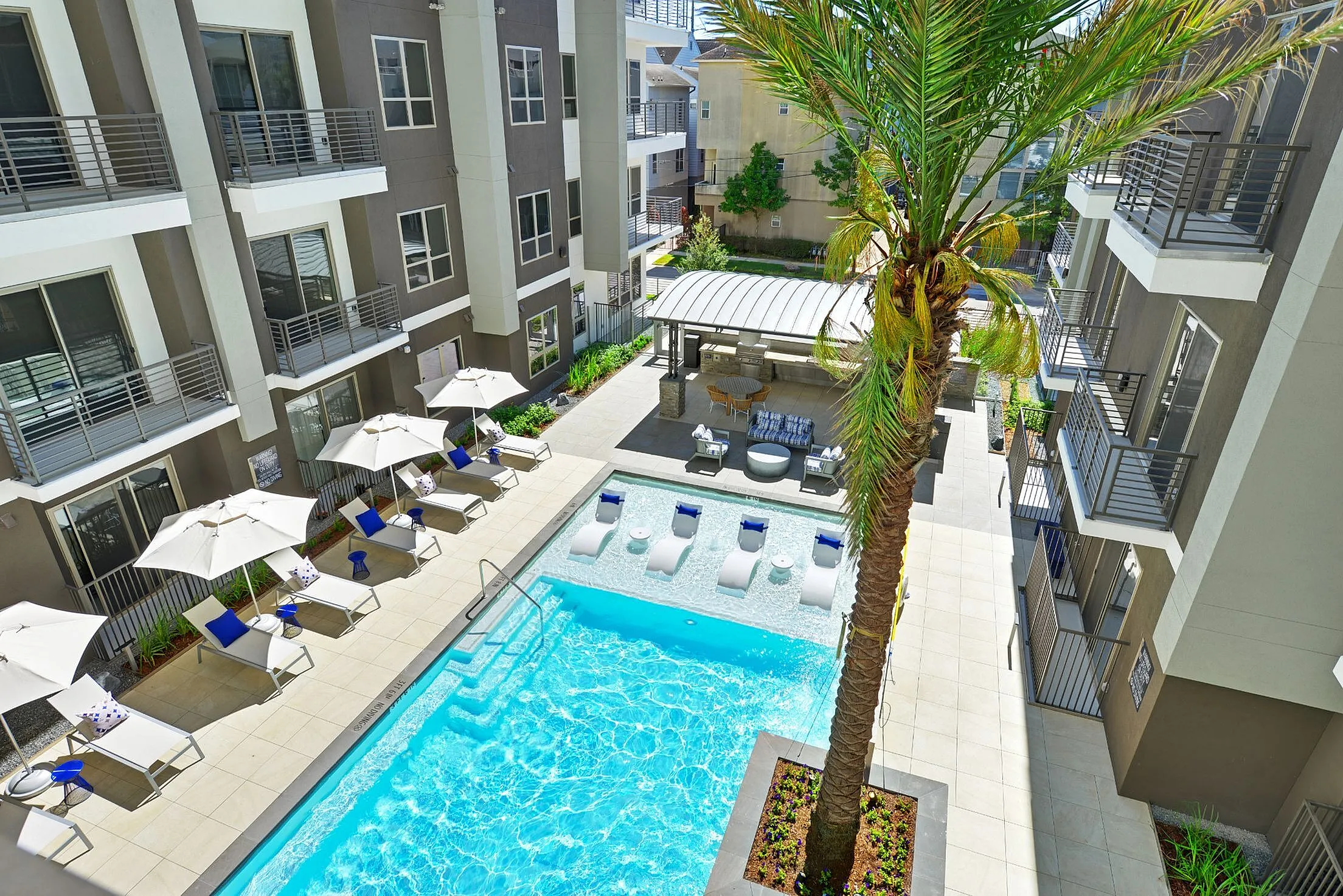 Aerial of pool courtyard with palm tree, lounge chairs and umbrellas, Houston, TX