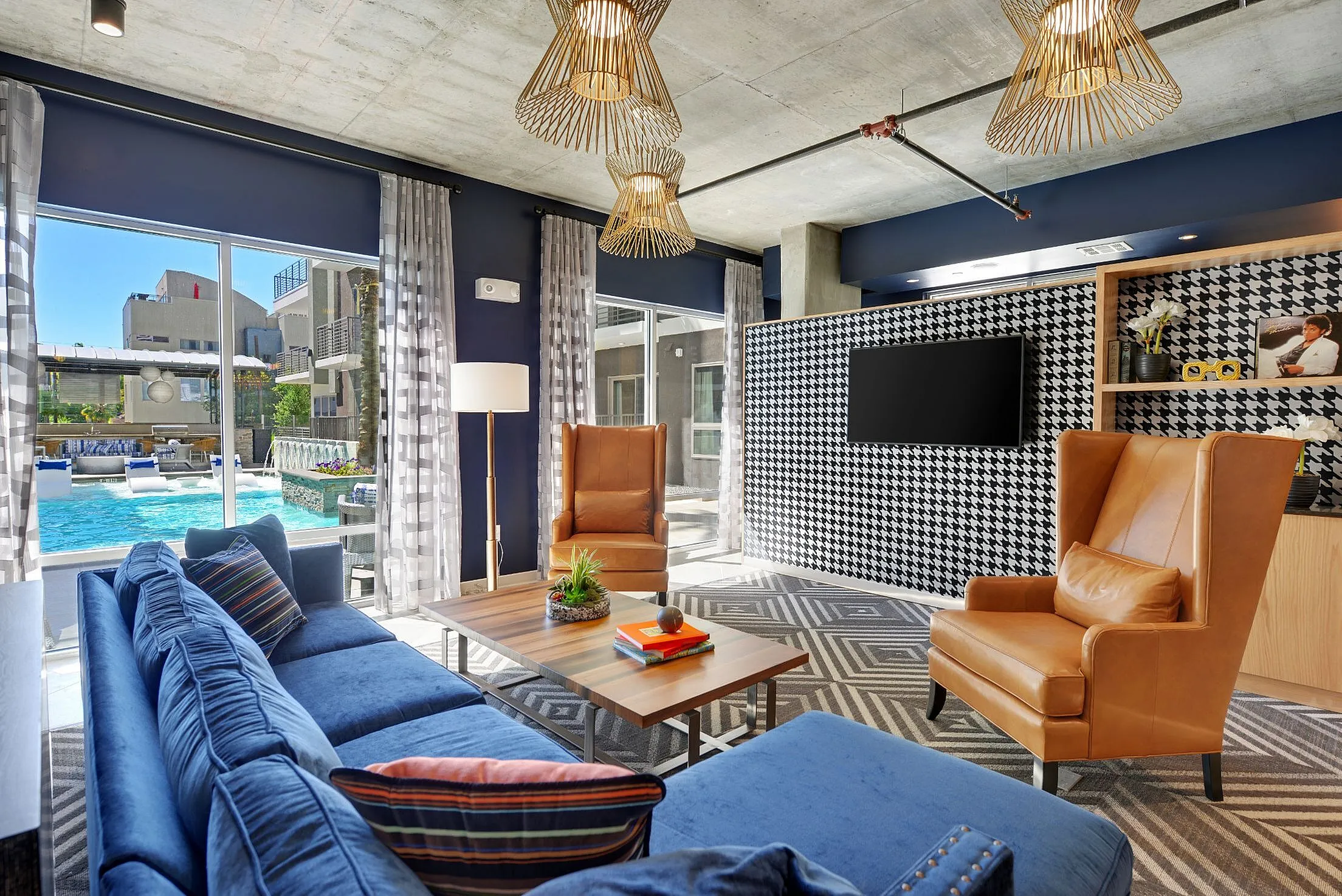 Resident lounge with blue sofa, leather armchairs and pool view