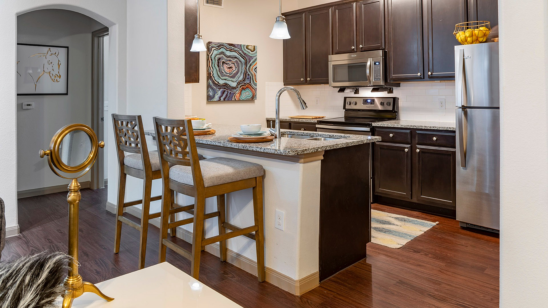 Modern kitchen featuring sleek stainless steel appliances, rich dark wood cabinets, and a stylish granite countertop with bar seating.