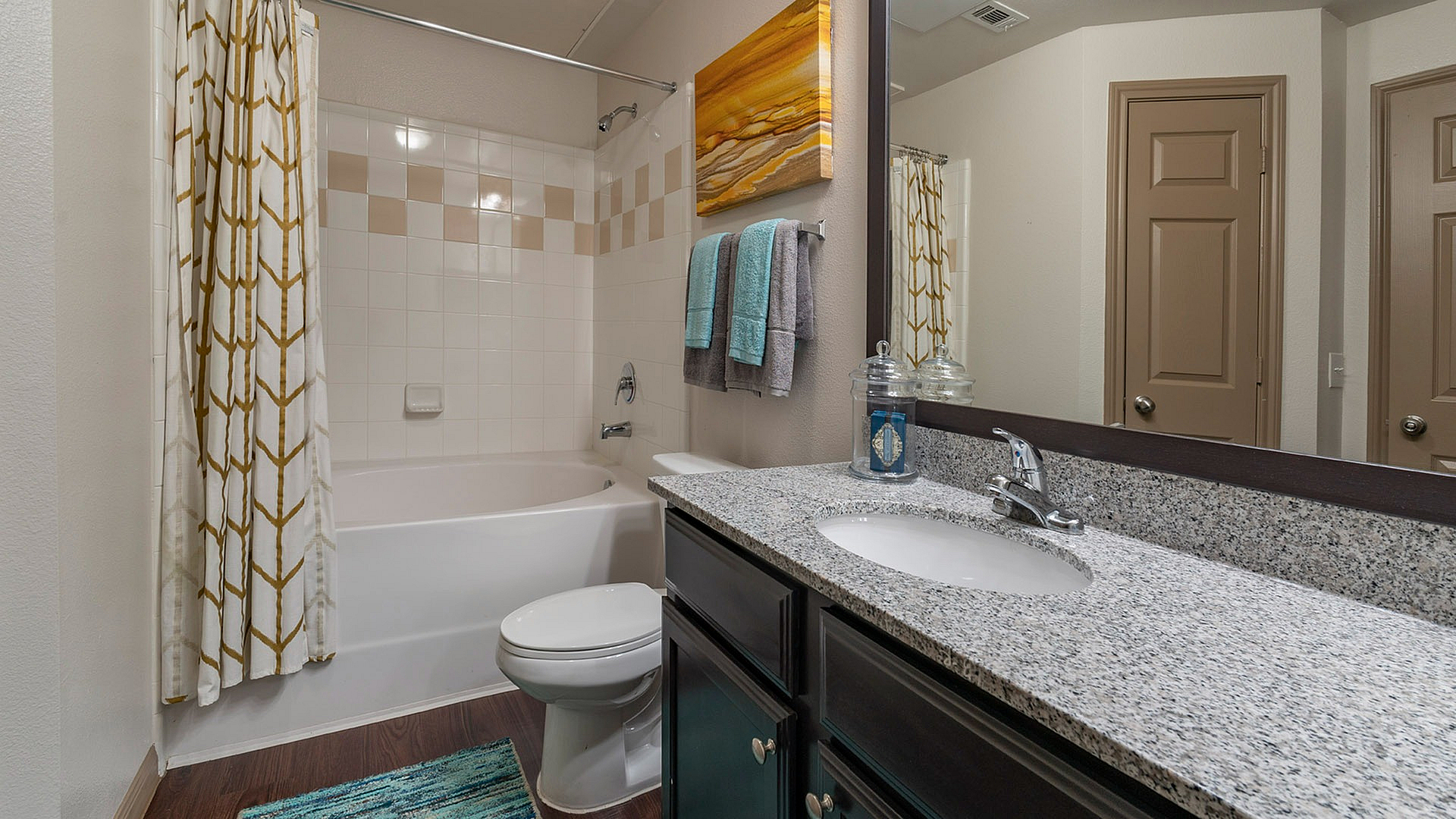 Elegant bathroom showcasing a sleek granite countertop, modern fixtures, and a relaxing bath with stylish curtains.