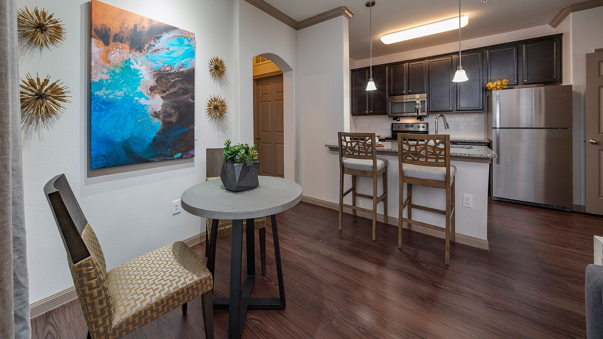 Chic apartment kitchen with sleek stainless steel appliances, modern pendant lighting, and stylish breakfast bar seating.