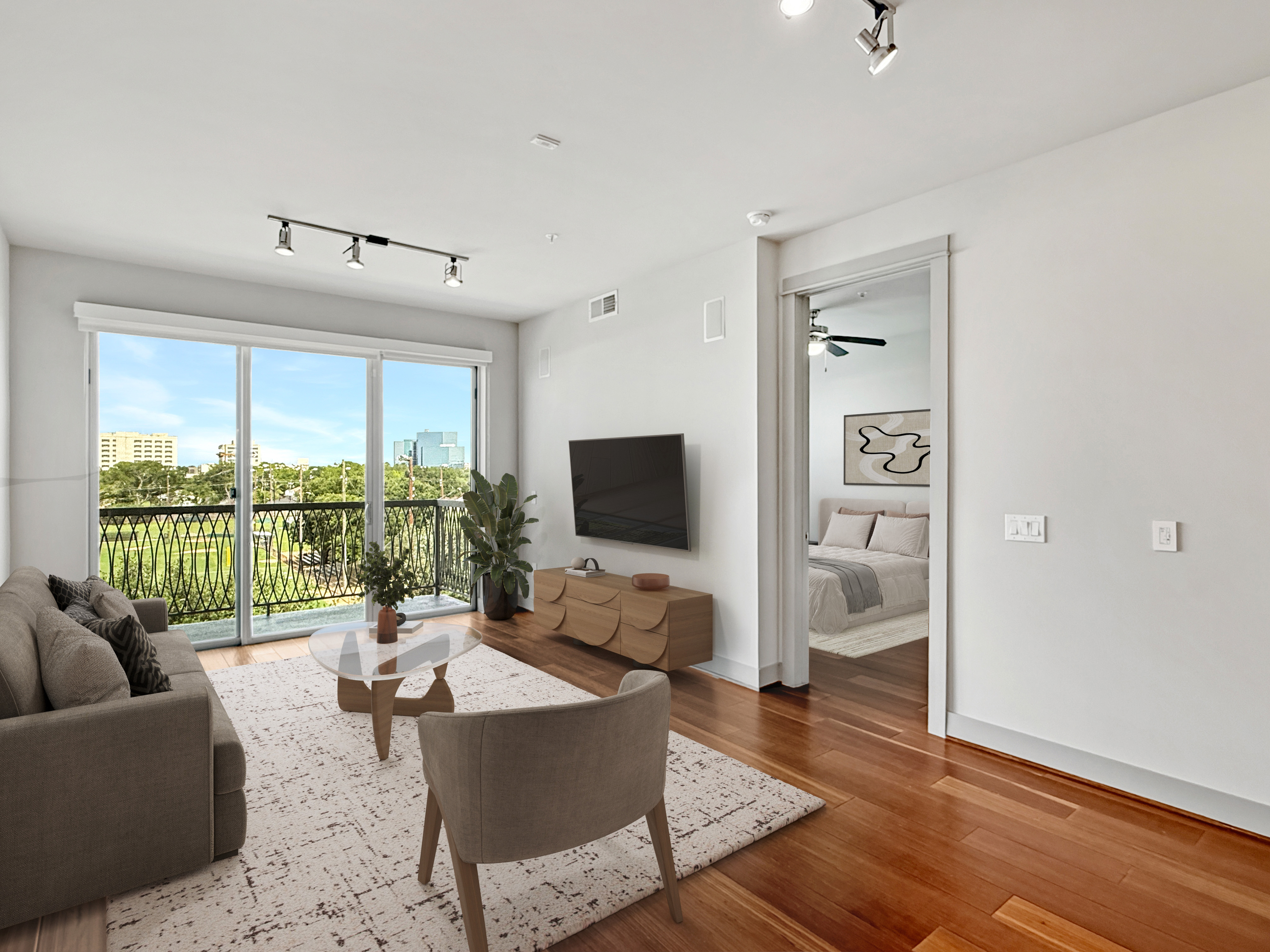 Bright and spacious living room with modern decor, featuring large windows and a stunning city view. Open access to an inviting bedroom.