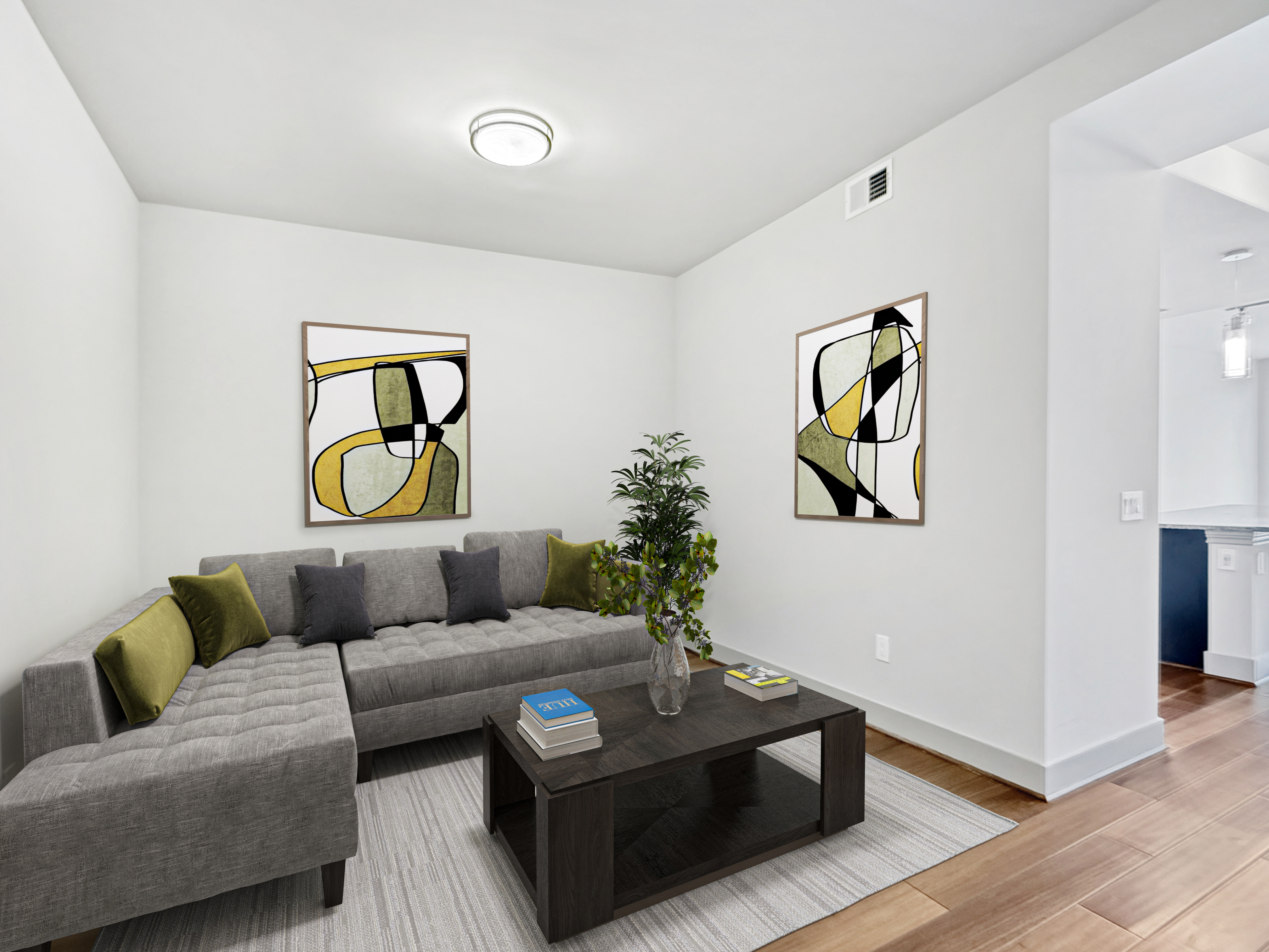 Contemporary living room with plush grey sectional sofa, modern art, and natural wood flooring.