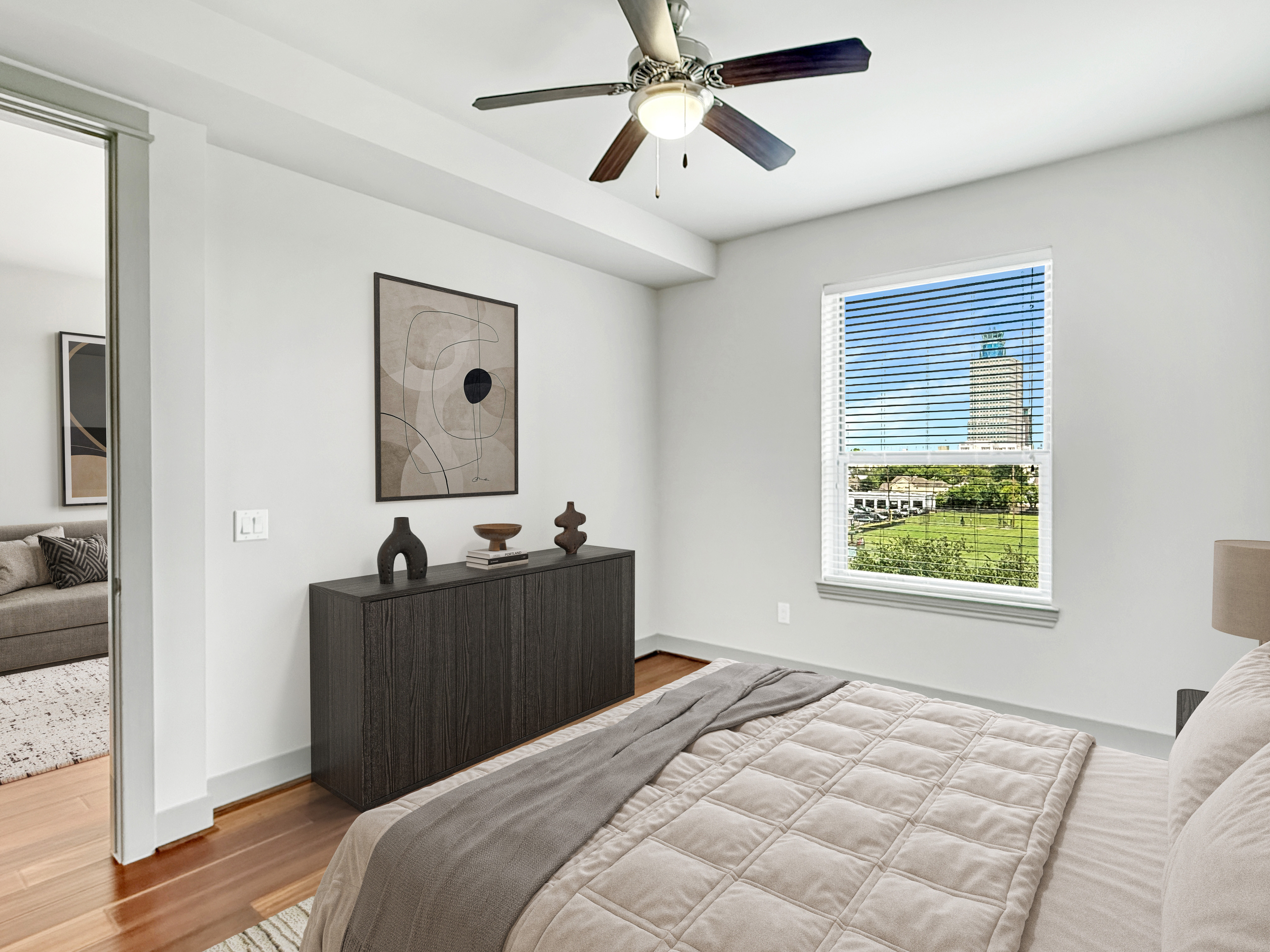 Bright and modern bedroom with elegant decor, featuring a large window with a scenic city view, and stylish furnishings.