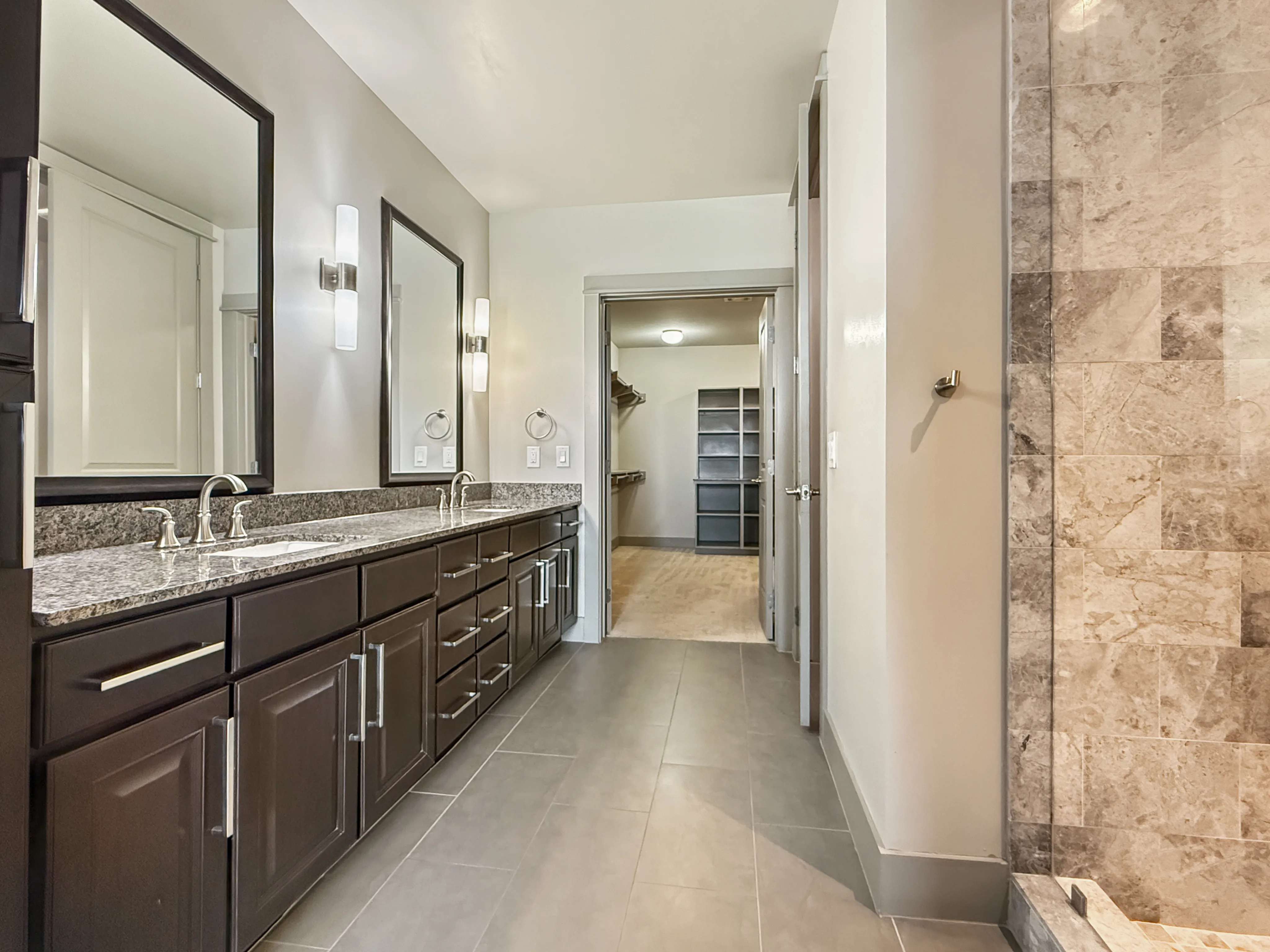 Elegant bathroom with dual sinks, granite countertops, and spacious walk-in closet entrance.