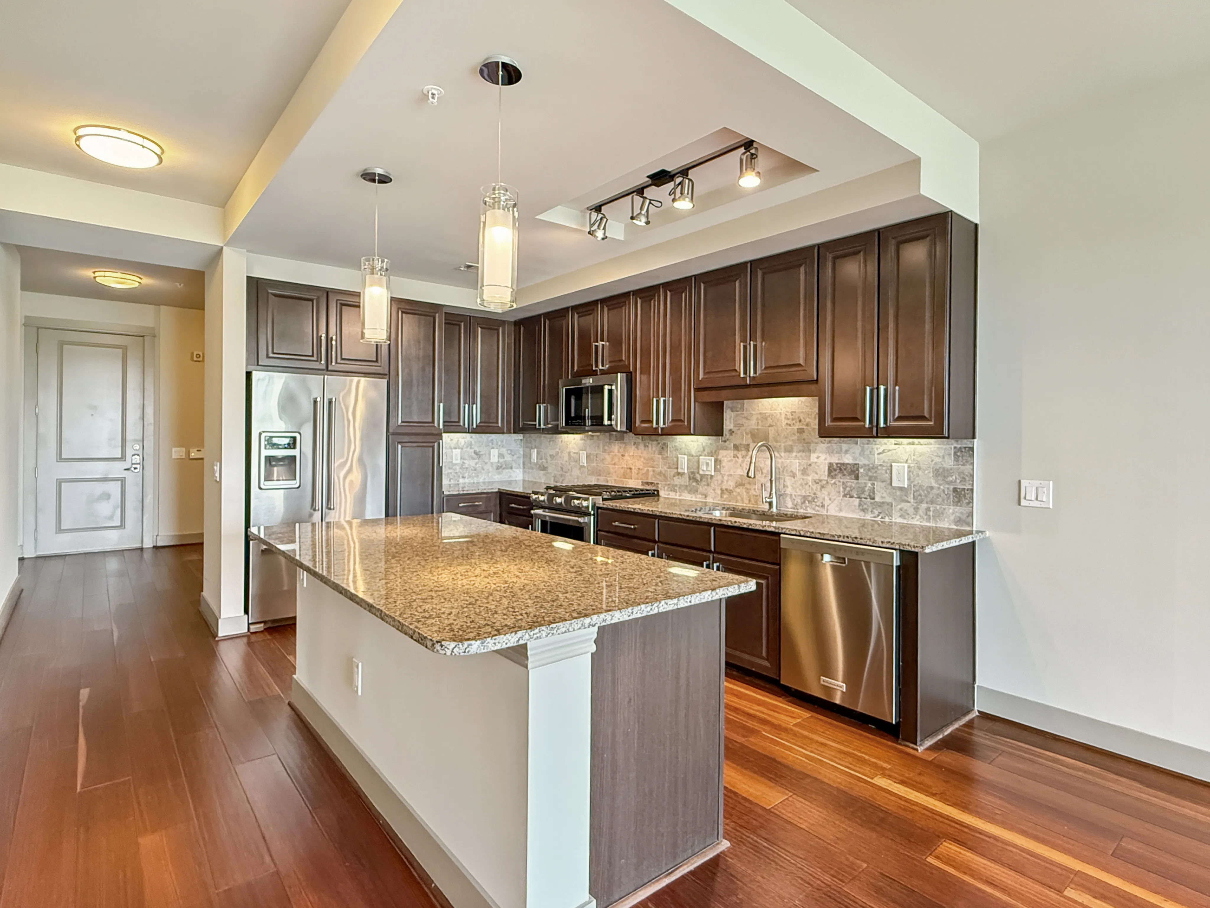 Elegant kitchen with sleek granite countertops, modern stainless steel appliances, and rich wood cabinetry, featuring an inviting open layout and stylish lighting fixtures.