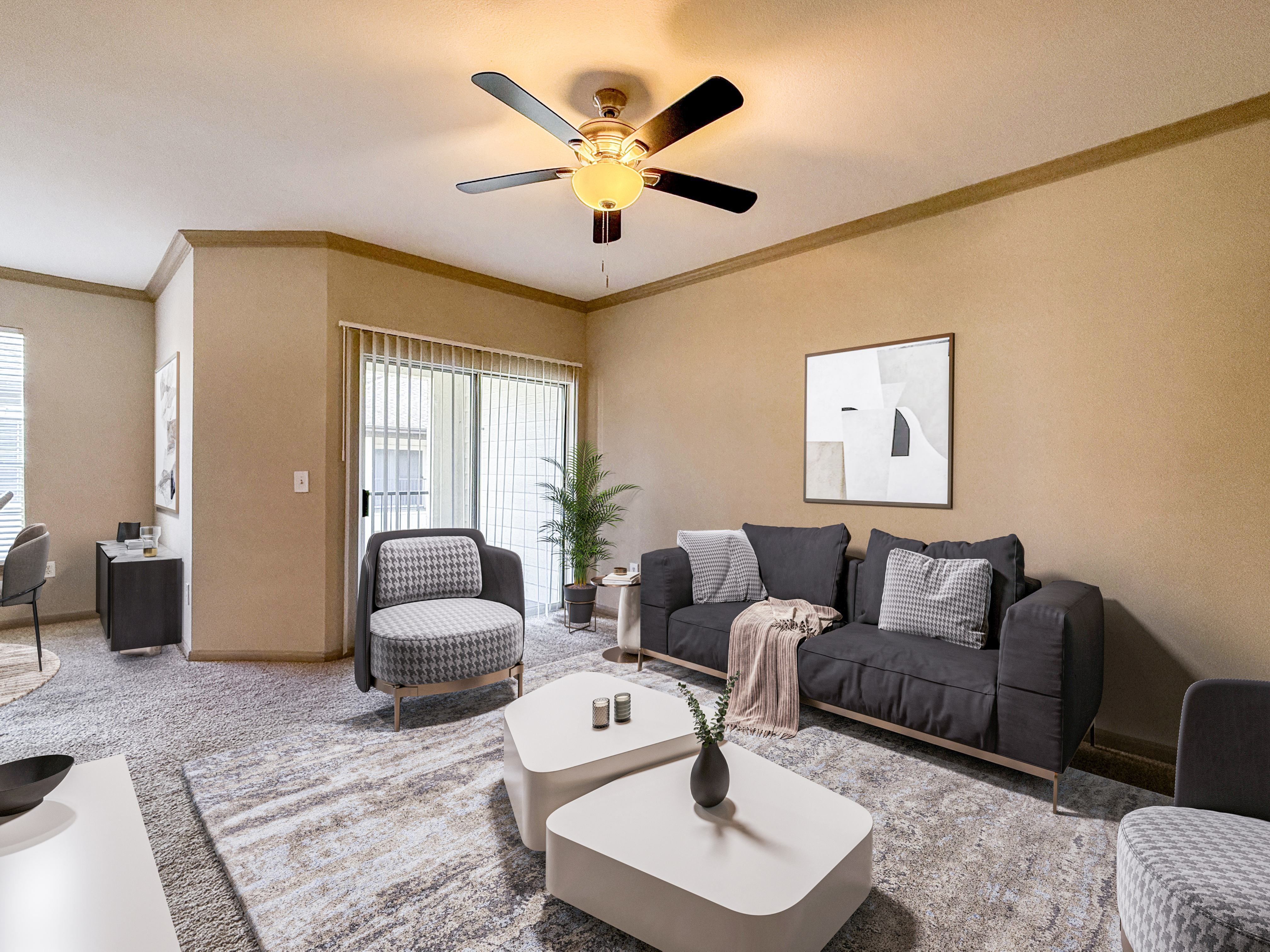 Chic living room with modern furnishings, featuring a cozy couch, stylish chairs, and elegant coffee tables under a warm ceiling fan glow.