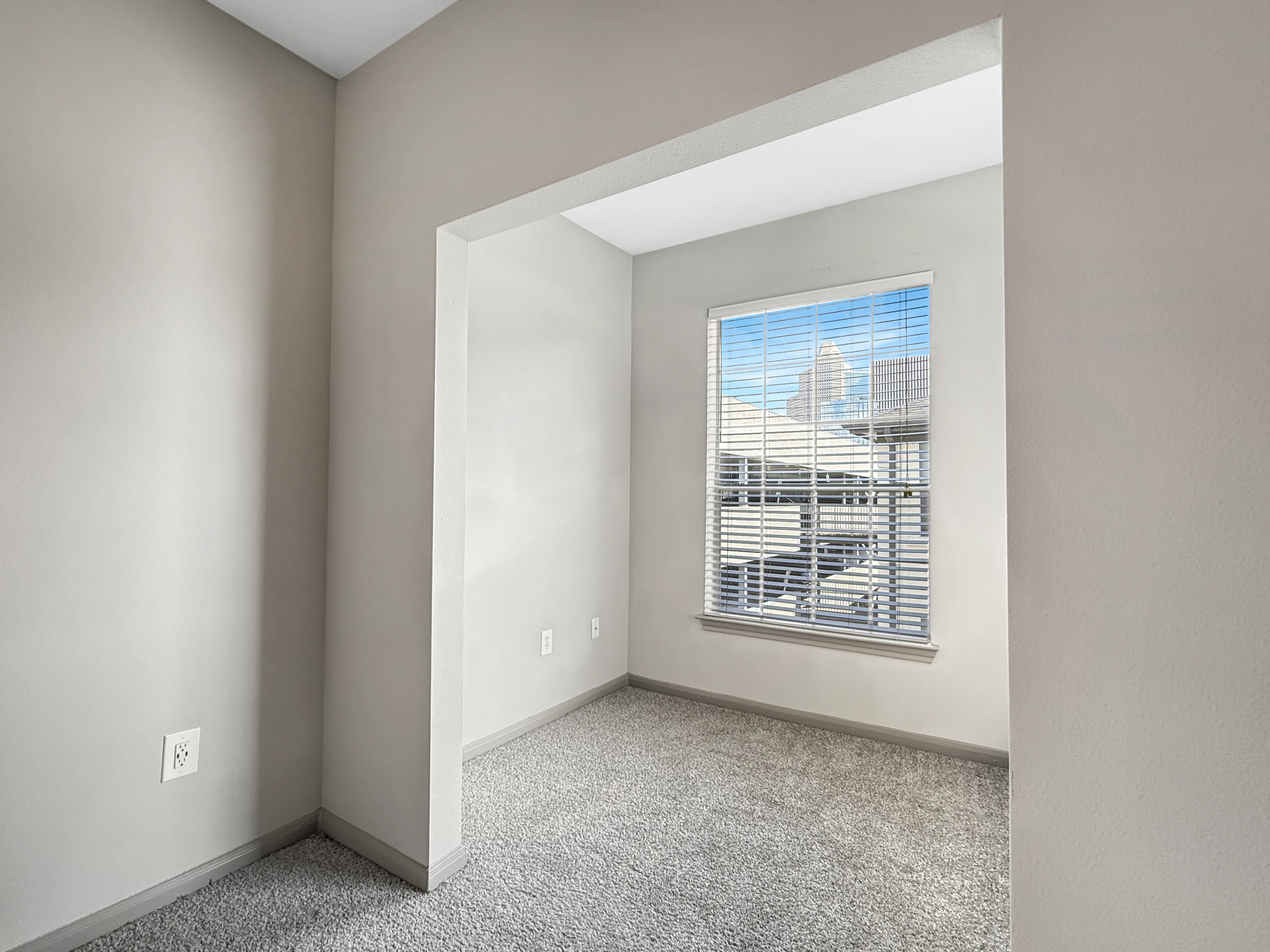 Bright and cozy nook with plush carpeting and large window offering urban views.