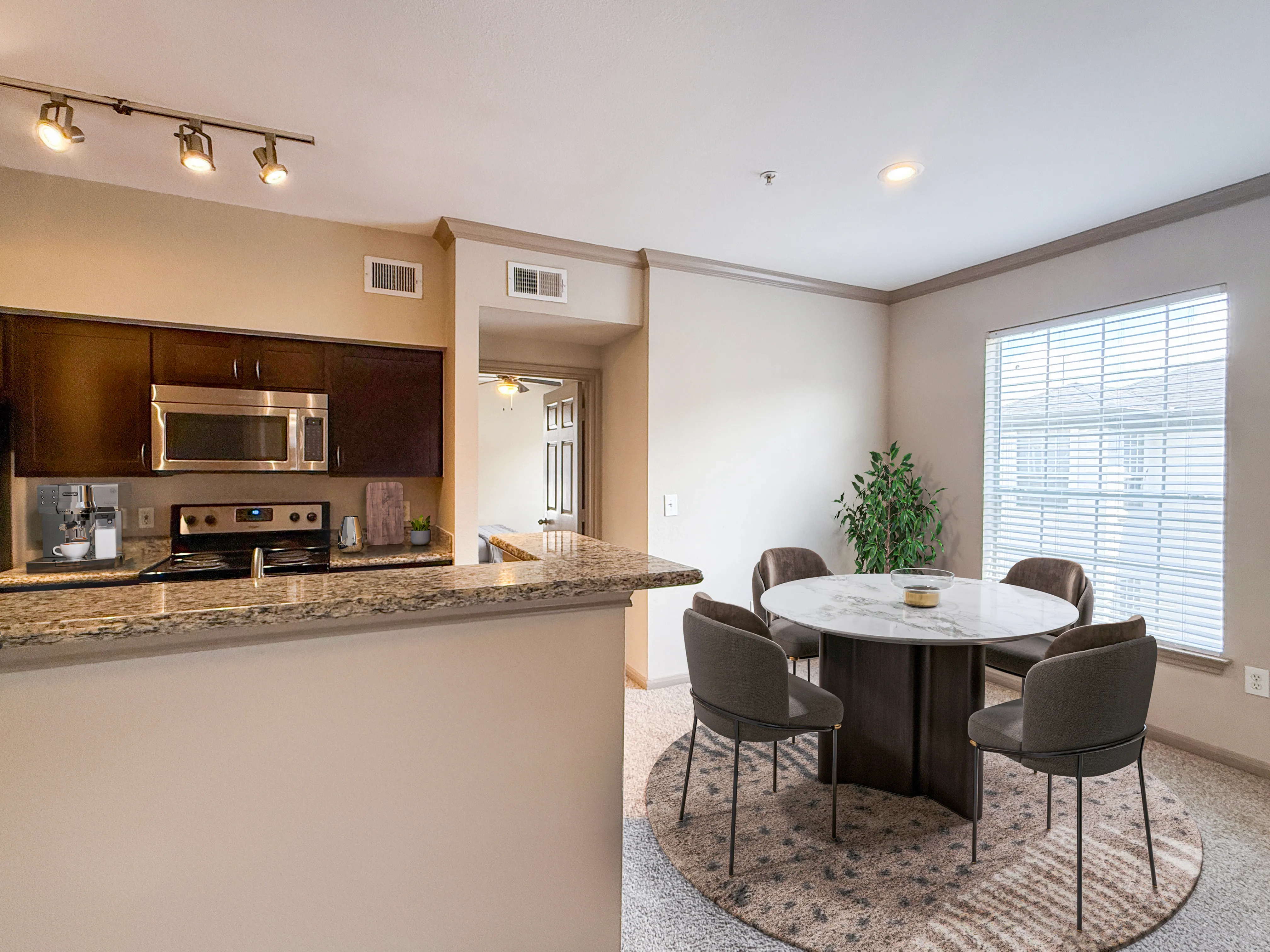 Modern open-concept kitchen and dining area featuring sleek granite countertops and a cozy round dining table with plush chairs.