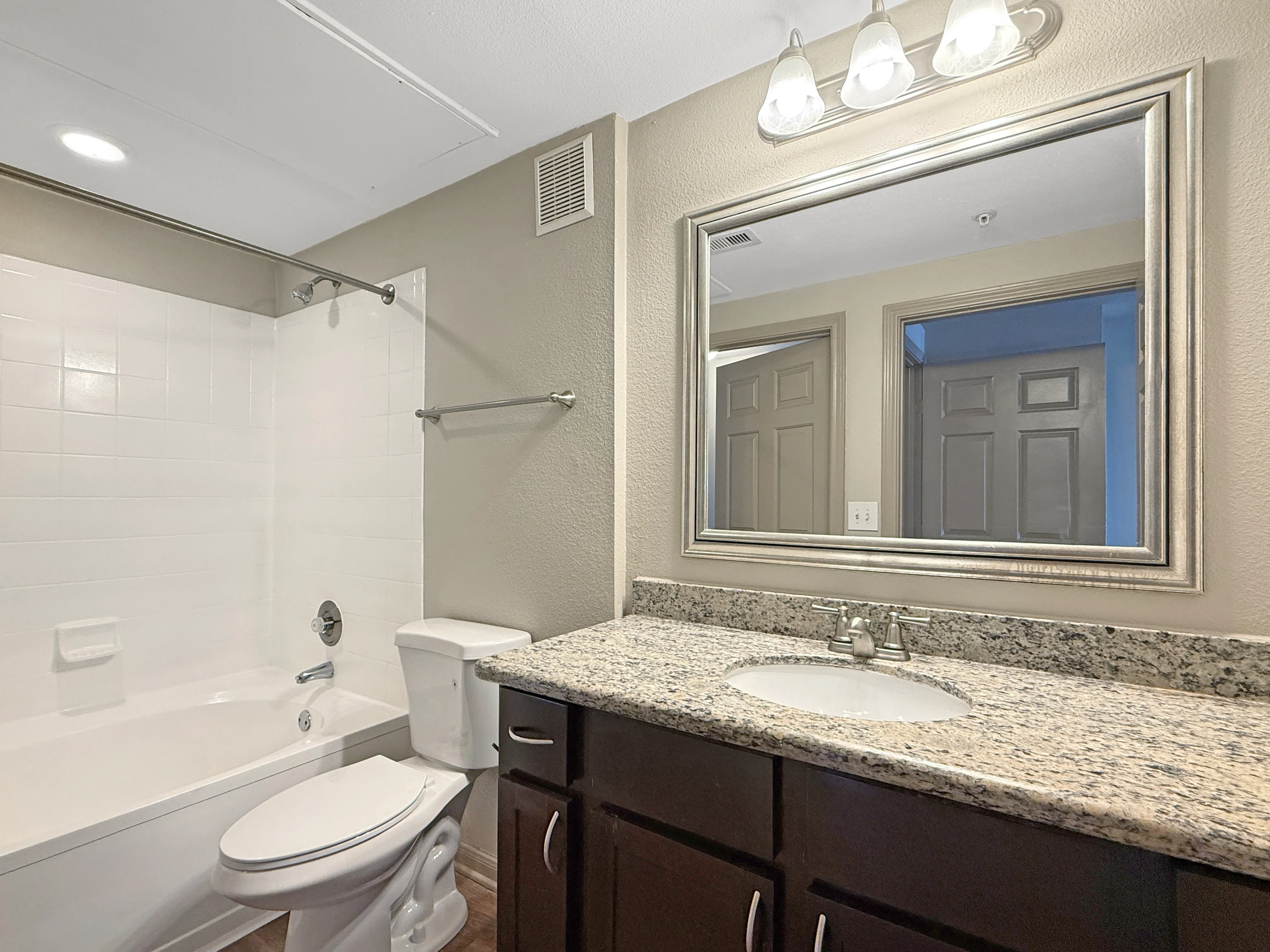 Elegant bathroom featuring granite countertops, stylish fixtures, and a classic white bathtub for a luxurious feel.