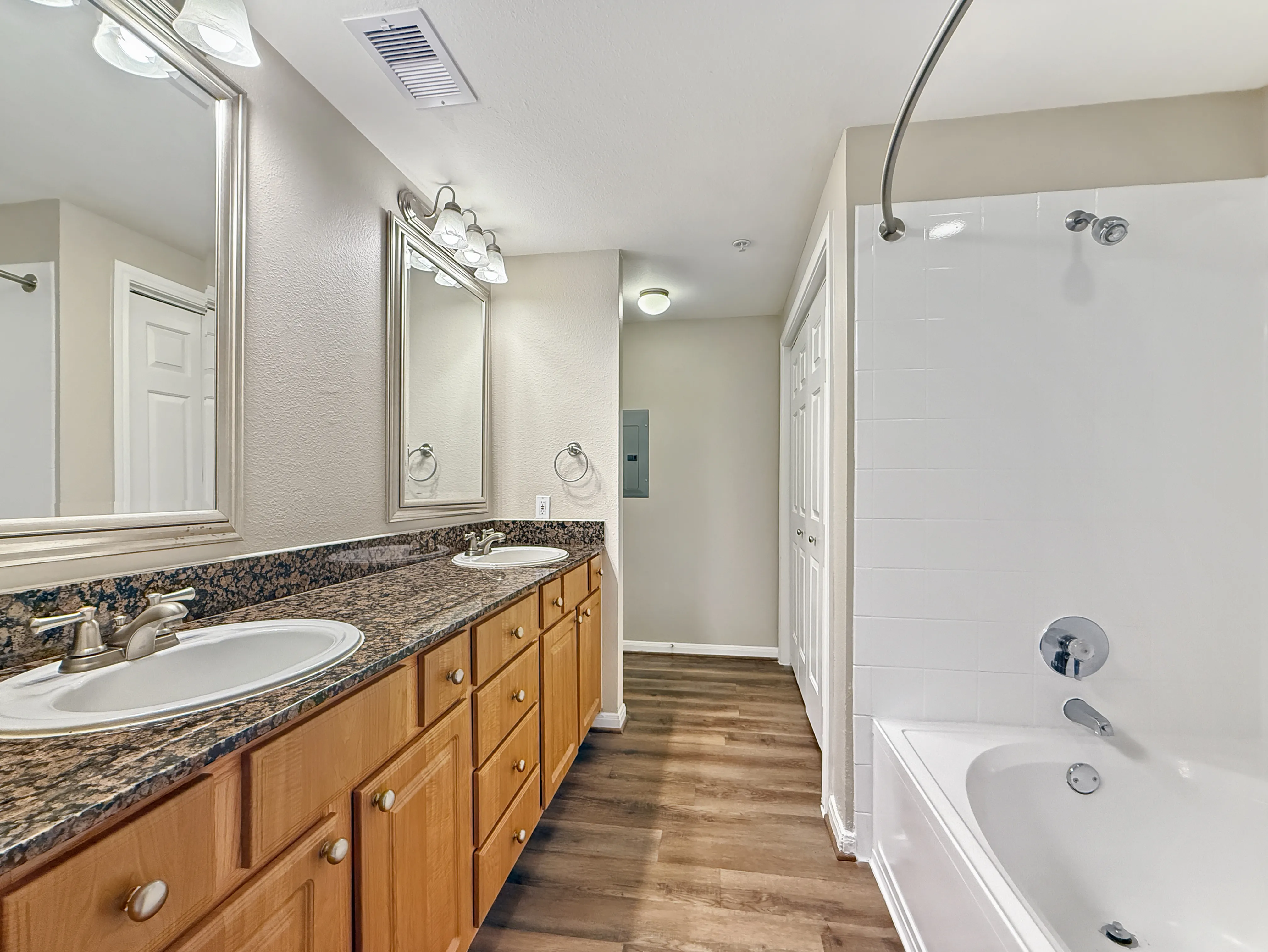 Beautifully designed bathroom with dual sinks, elegant granite countertops, and a spacious bathtub, perfect for relaxation.