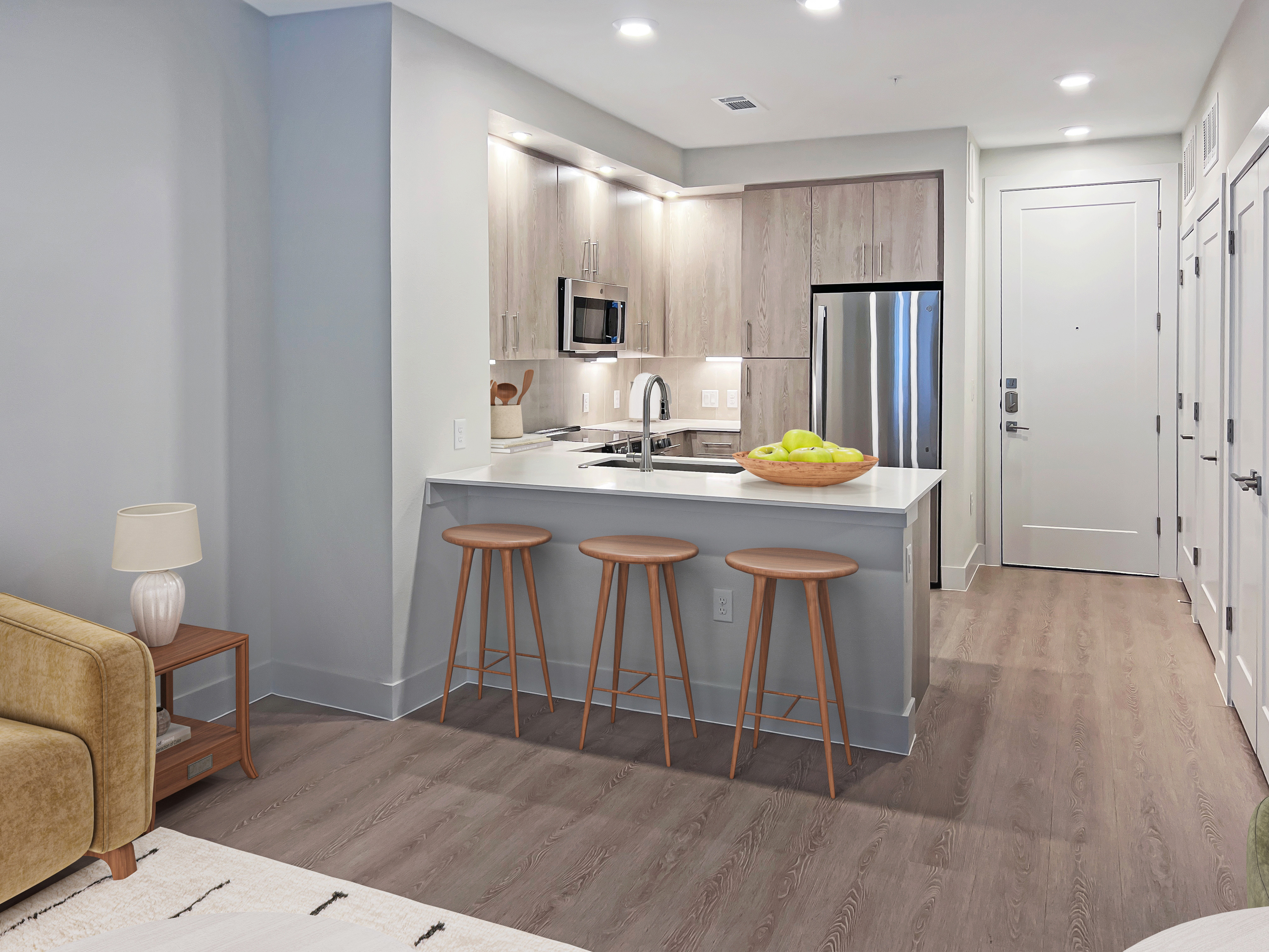 Modern apartment kitchen with sleek cabinetry, stainless steel appliances, and a cozy breakfast bar with stylish barstools.