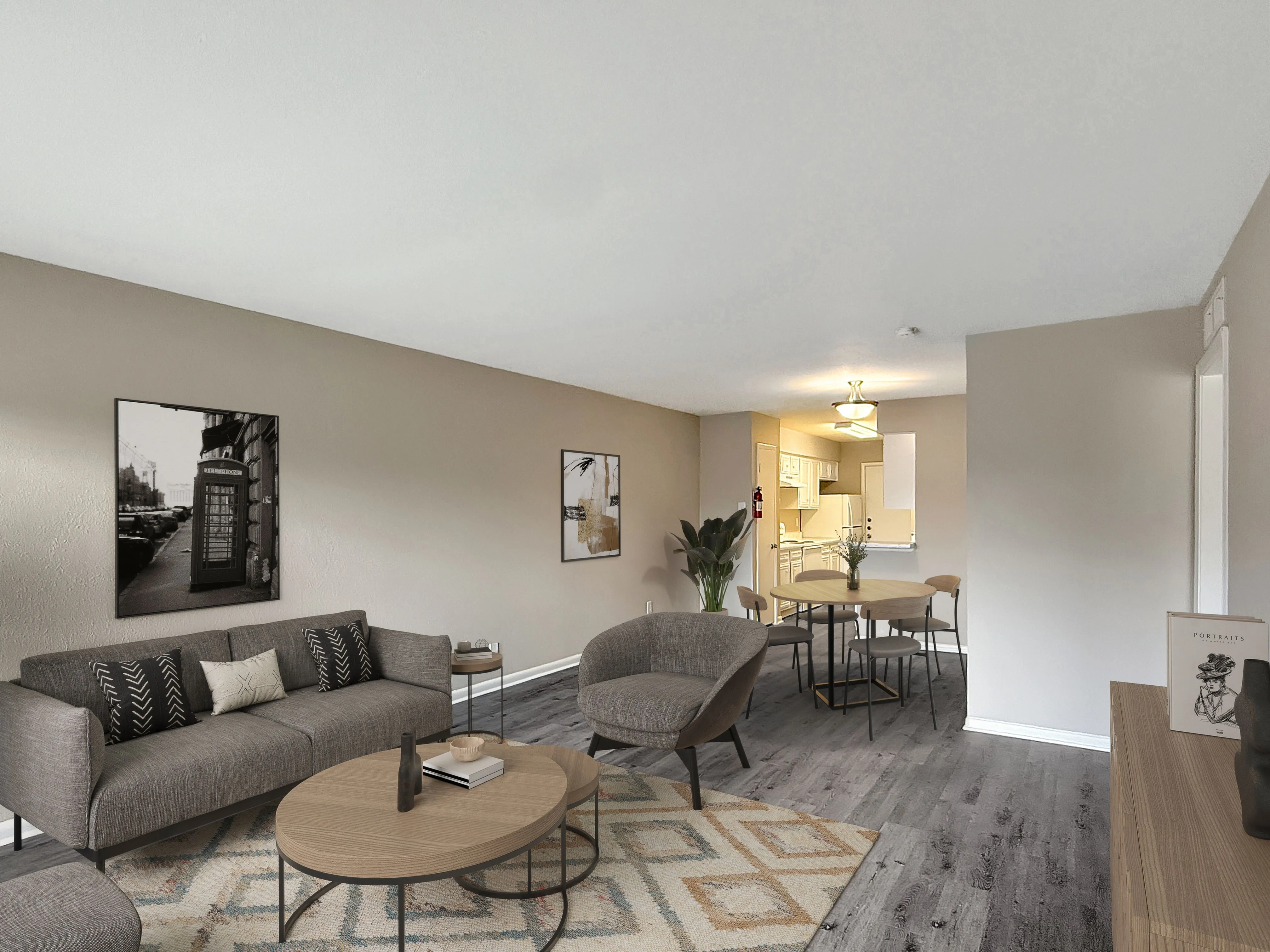 Modern apartment living area with elegant gray furniture, stylish wall art, and open dining space leading to a bright kitchen.