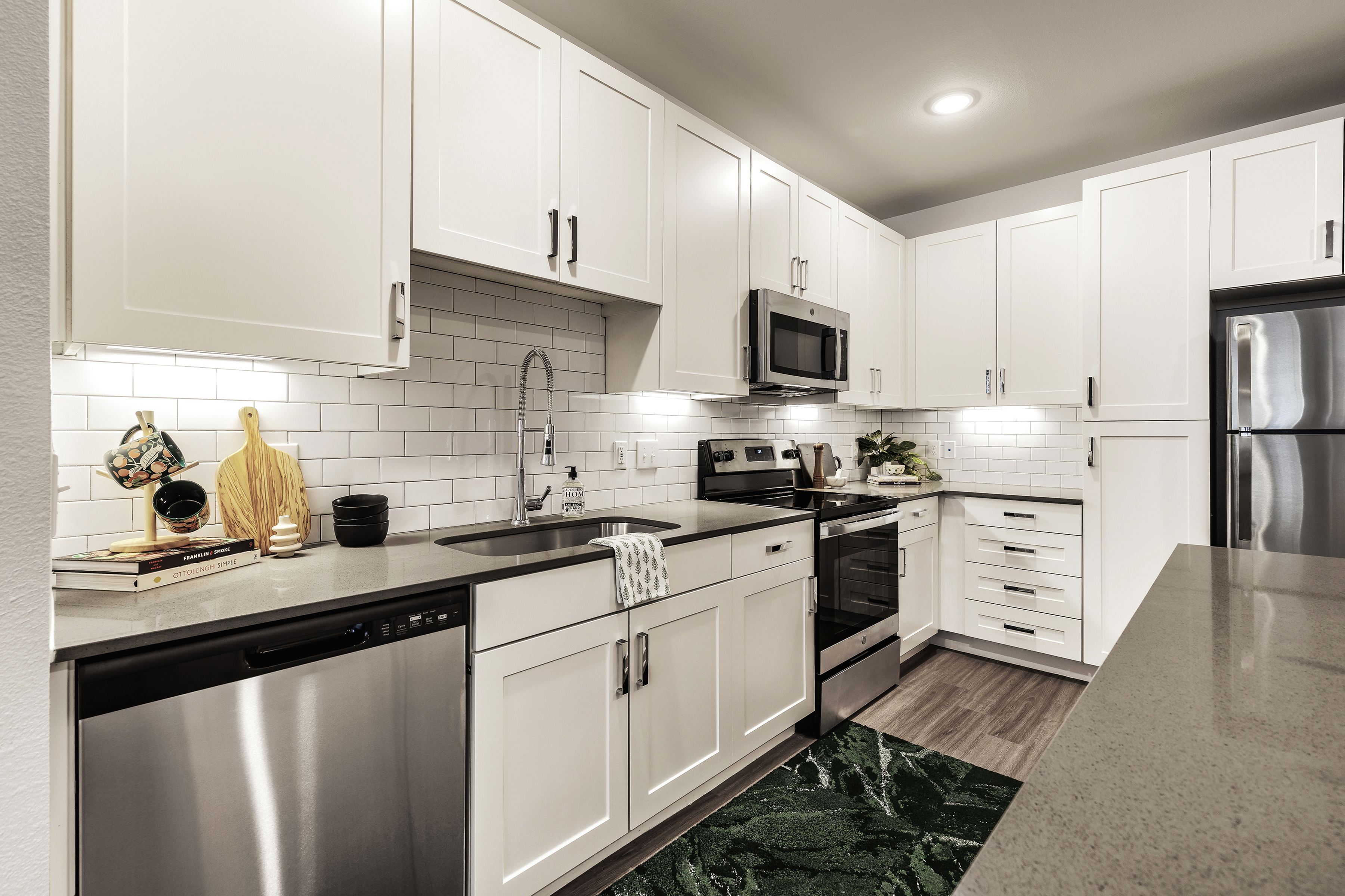 Sleek modern kitchen with stainless steel appliances, white cabinetry, and subway tile backsplash.
